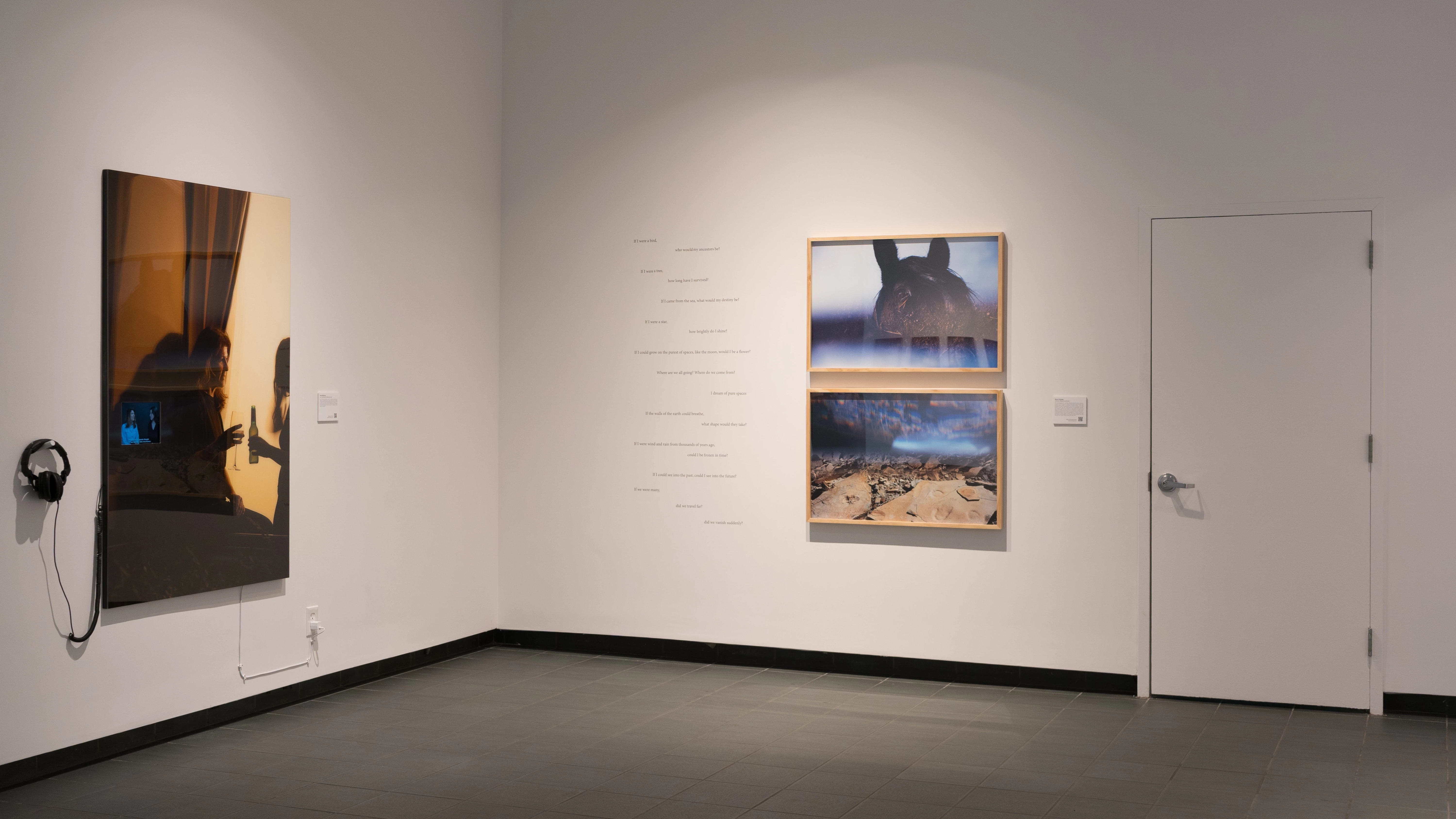 A corner wall in SVA’s Gramercy Gallery with one image on the left with headphones resting beside it, and two photos on the right, with text written on the wall beside it.