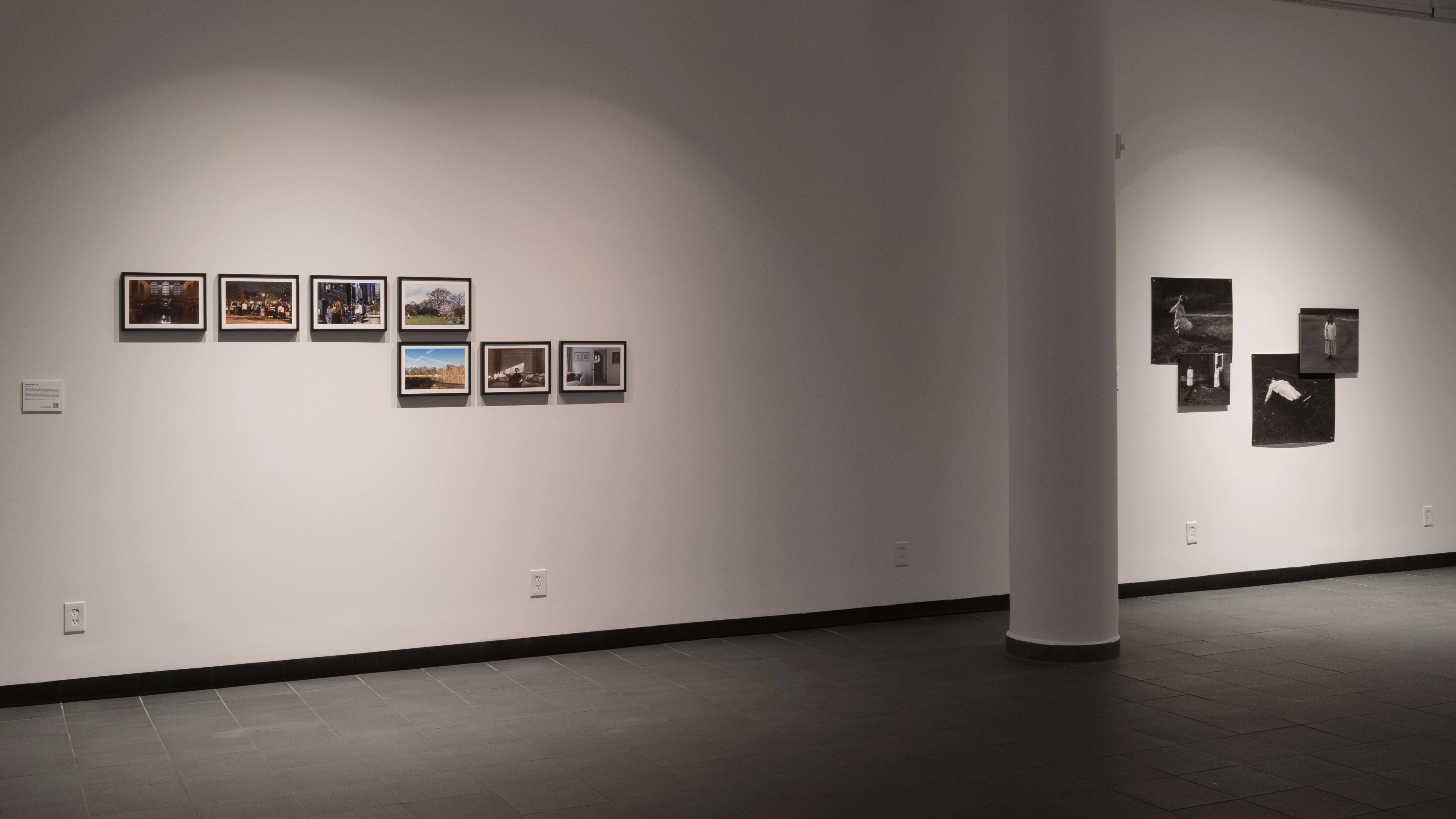 A wall with seven small photographs lined on the left, and four photos pinned to the right, with a structural pillar in between.