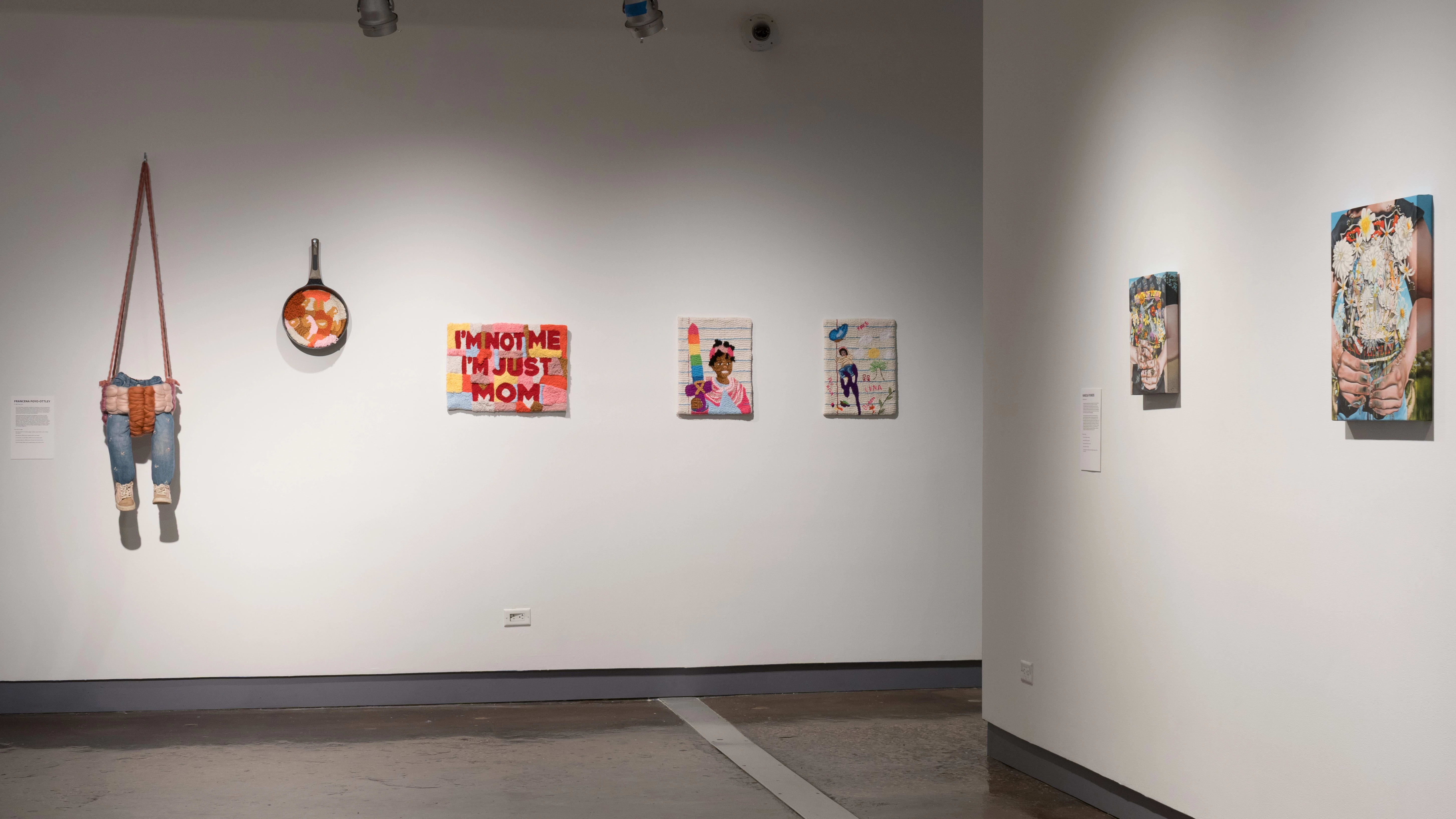 The second gallery with several textile artworks hung on the far wall and a few paintings on the right wall.