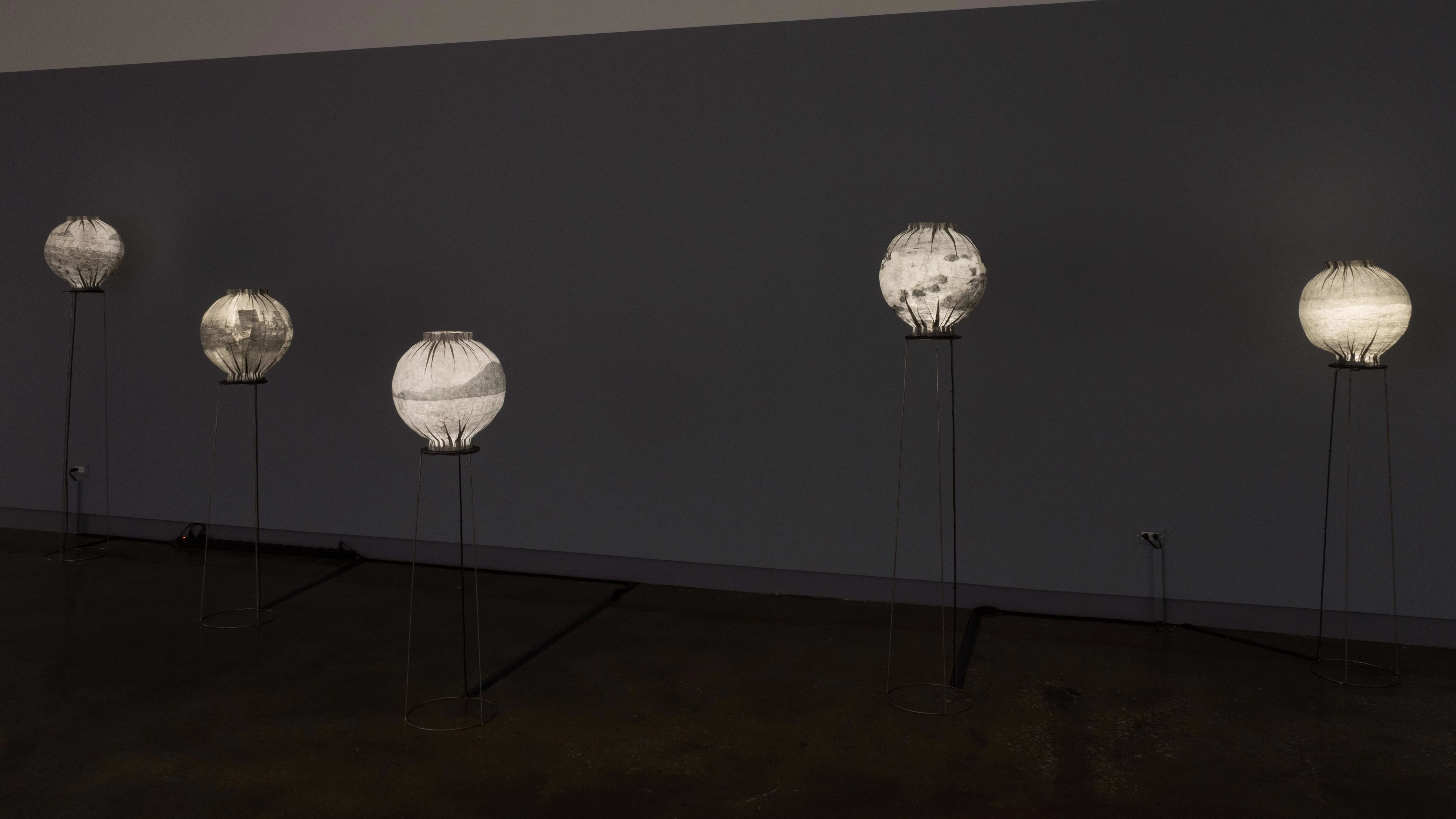A dark room with several glowing paper lanterns on wire pedestals.