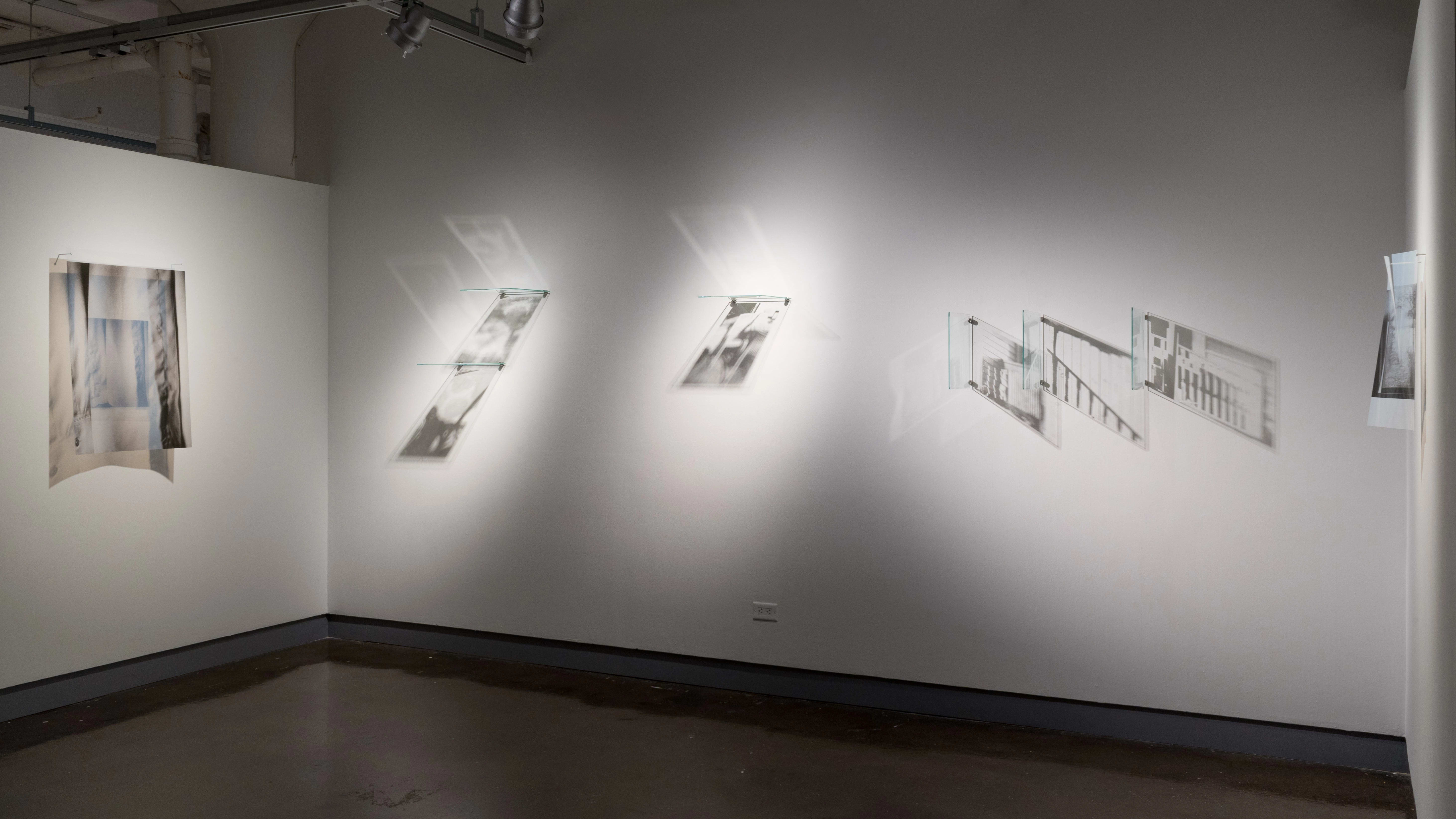 A wall showcasing several glass pane artworks that cast shadows on the wall.