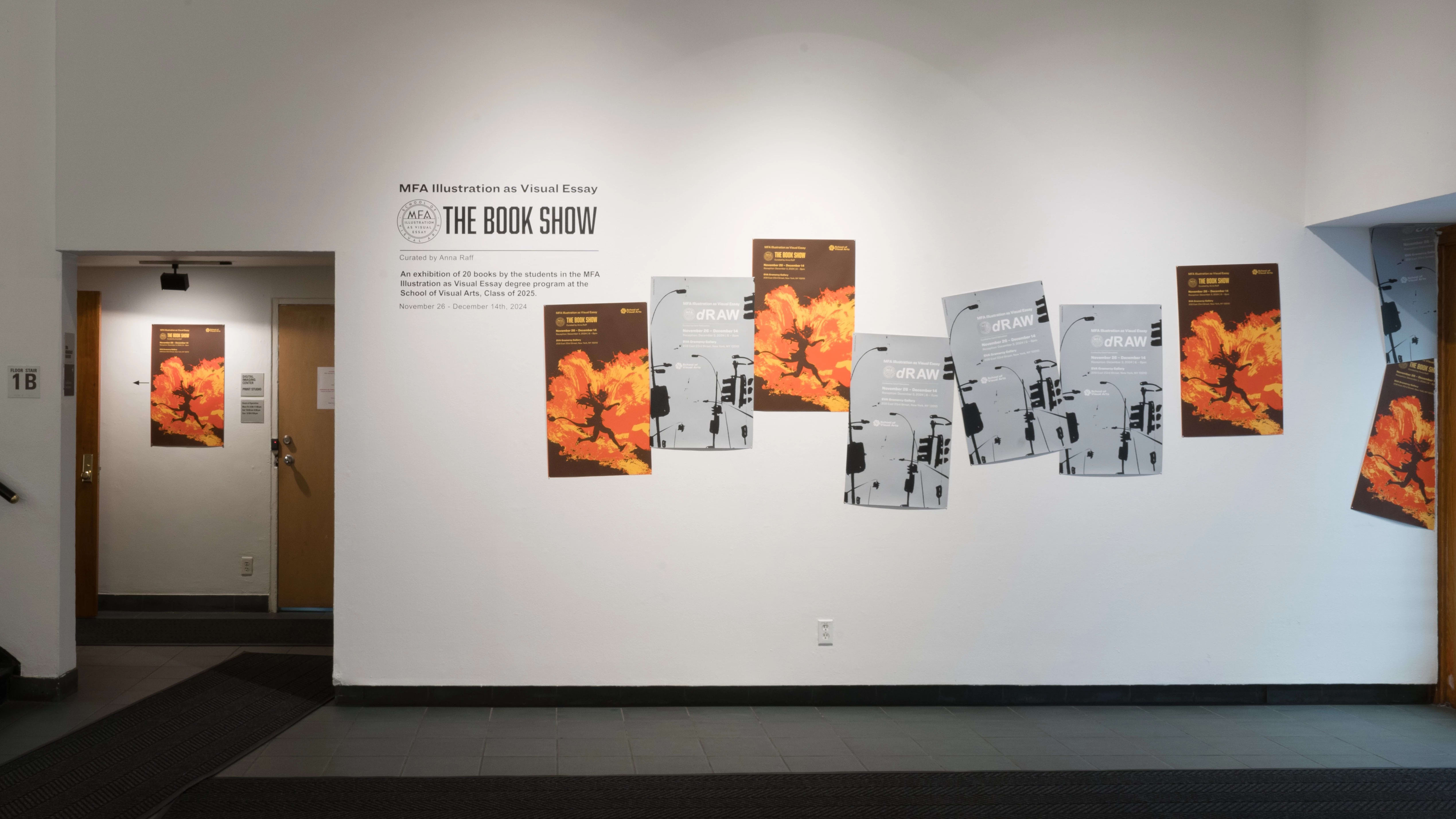 Wide shot of the right hand wall of the Gramercy front gallery. It shows the posters for “dRAW” and “The Book Show,” as well as the title vinyl for “The Book Show.” to the left is the hallway leading to the back gallery which hosts “The Book Show.”