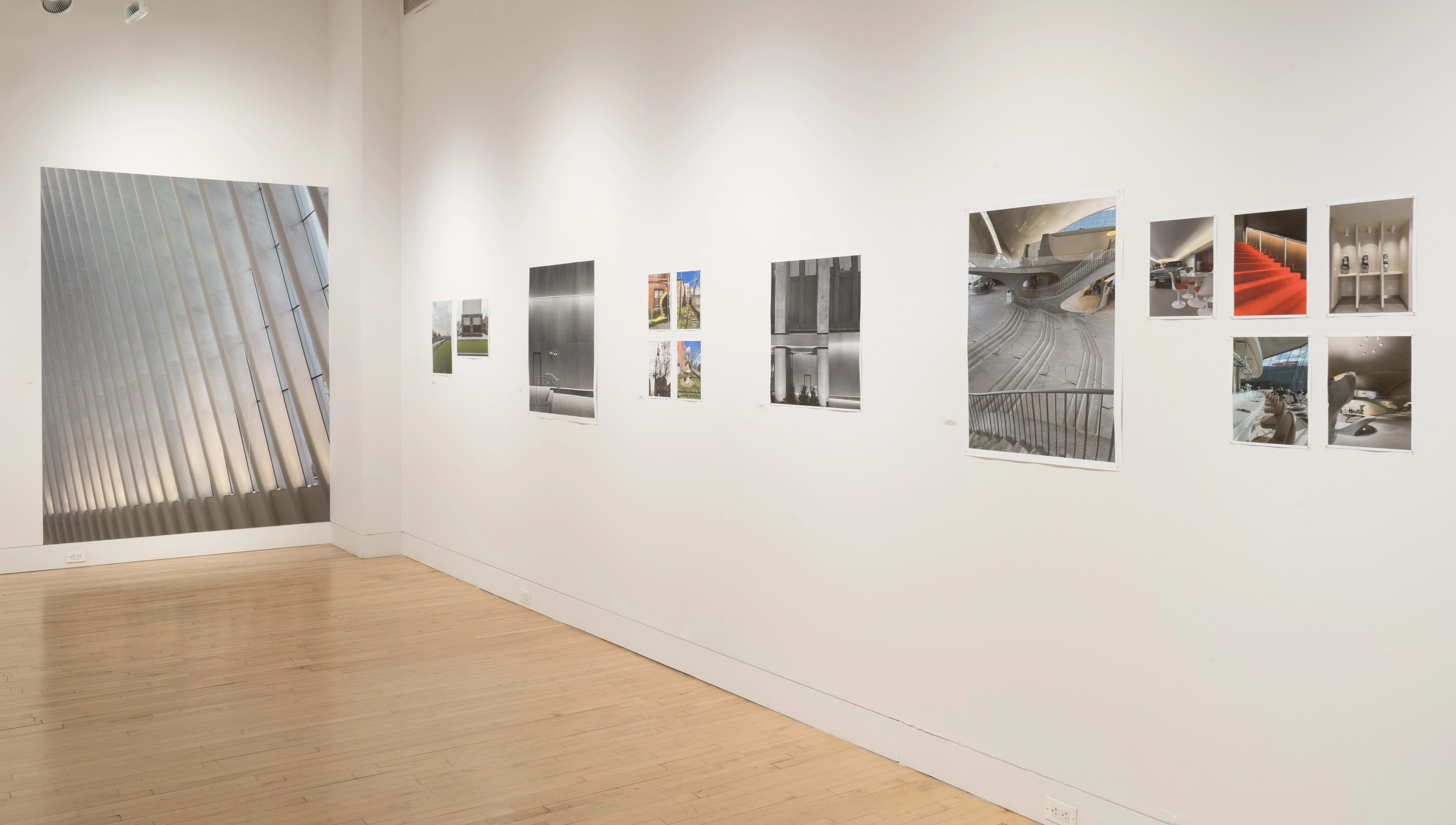 Angled shot of one wall in the Flatiron Gallery, showing multiple prints of industrial moments in varying sizes lining the walls, and an extra large print in grey on the back wall.