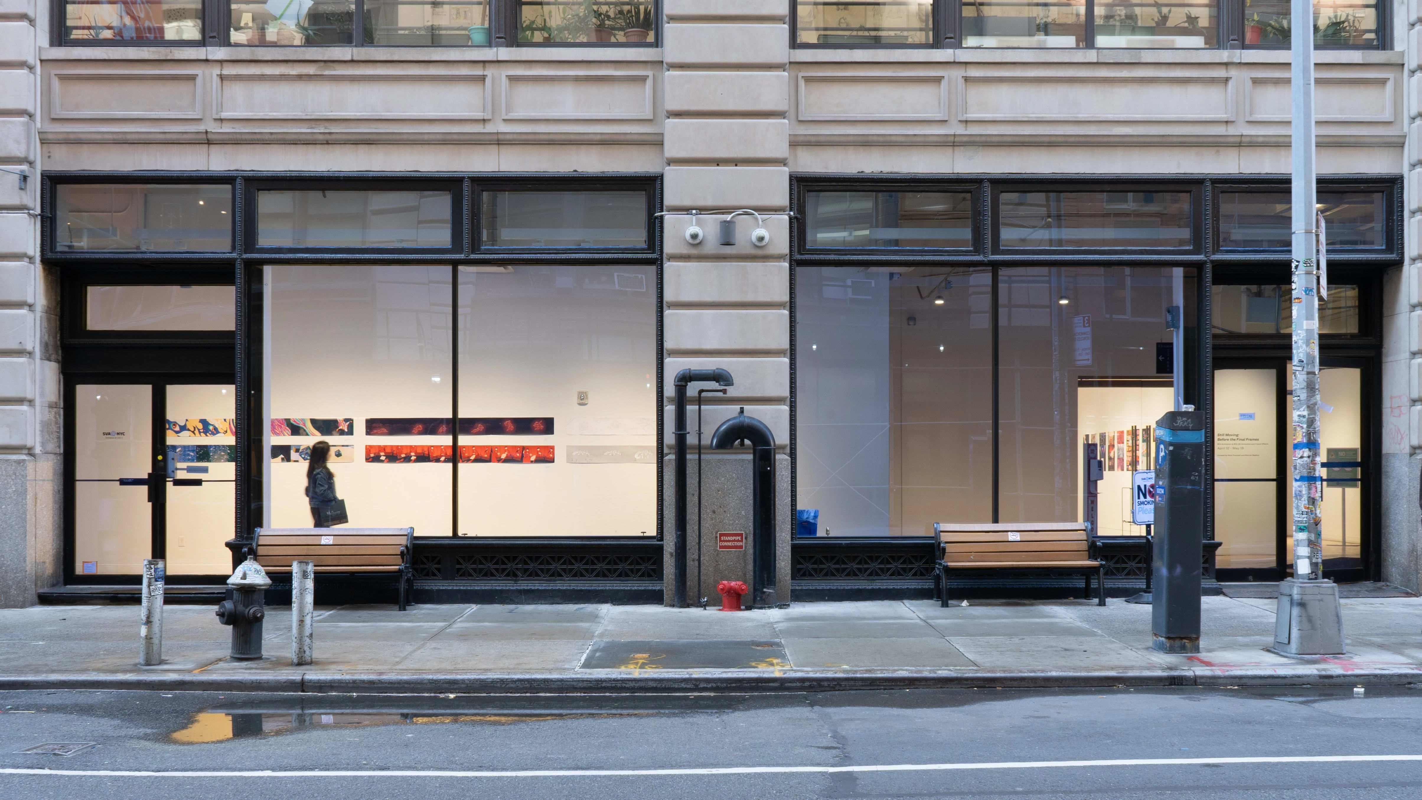 A view from outside the SVA Flatiron Gallery Windows shows a visitor looking at the prints.