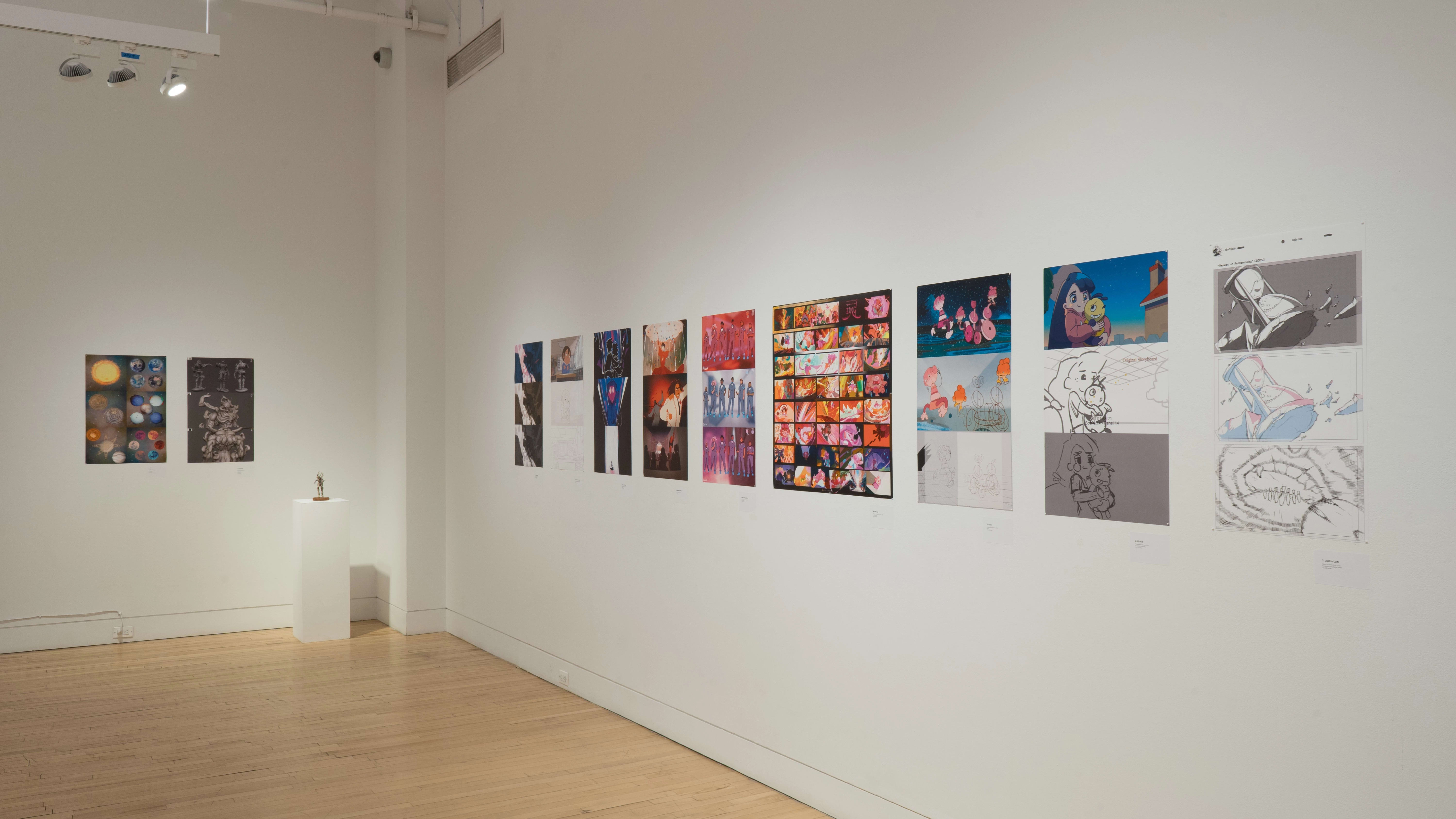 An angled shot of the SVA Flatiron Gallery's east wall, showing many colorful prints by BFA Animation students pinned up; a sculpture sits atop a pedestal near the back wall.