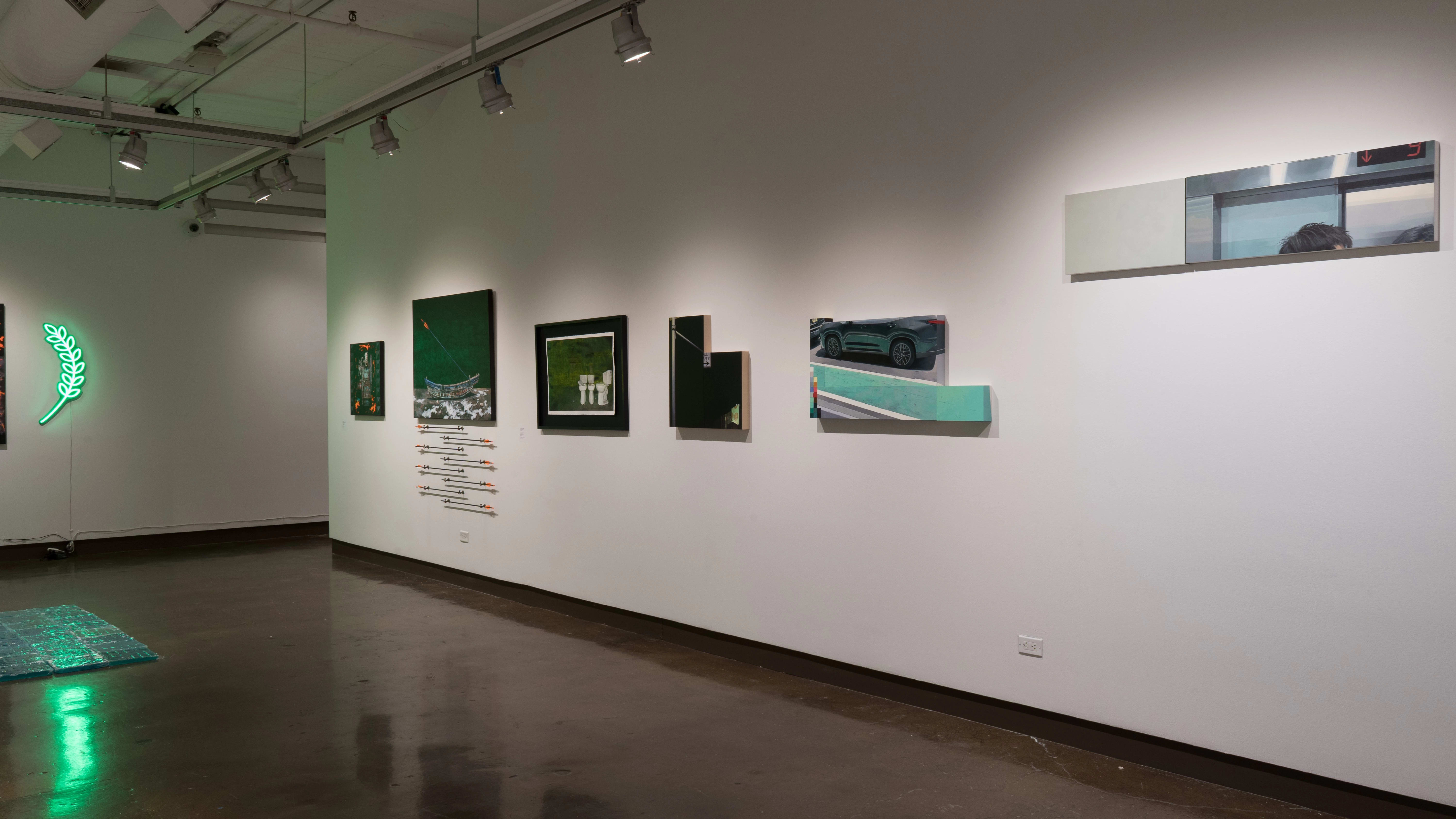 Along one wall of gallery two, paintings on geometric-shaped panels look as if part of a picture has been selected from a larger whole. Beyond them, a painting of a canoe hangs above a set of arrows mounted on the wall.