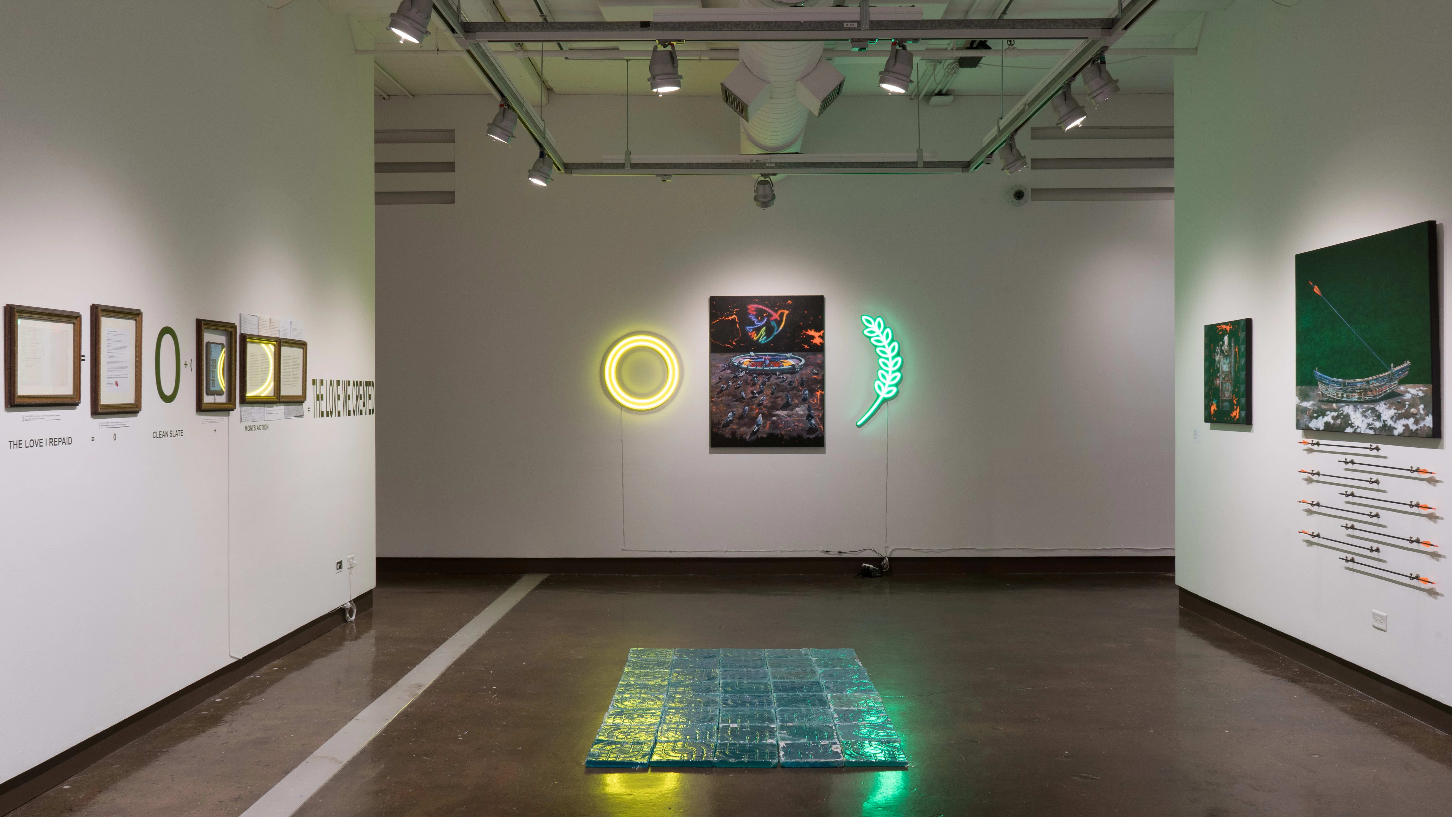 On the far wall in gallery two, a painting of pigeons in a space-like environment hangs between two neon lights. The yellow and green lights reflect on blue, textured resin tiles that have been arranged on the floor. Framed works hang on the left wall, and canvas paintings hang on the right.
