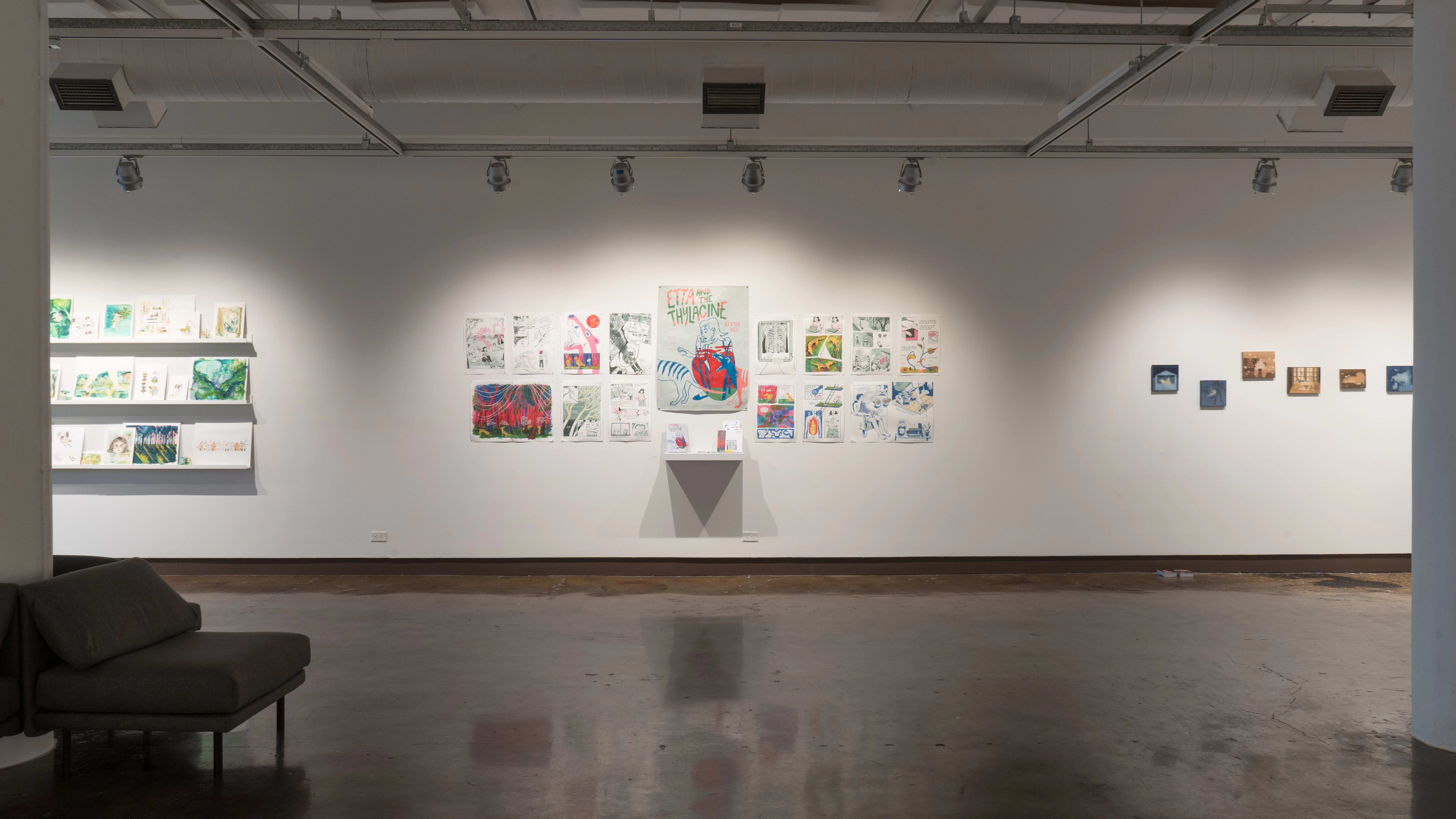 A straight view of the west wall at the SVA Chelsea Gallery. There are three projects visible on the wall: watercolor paintings on shelves on the left, two rows of pinned illustrations in the middle, and small paintings on panel on the right.