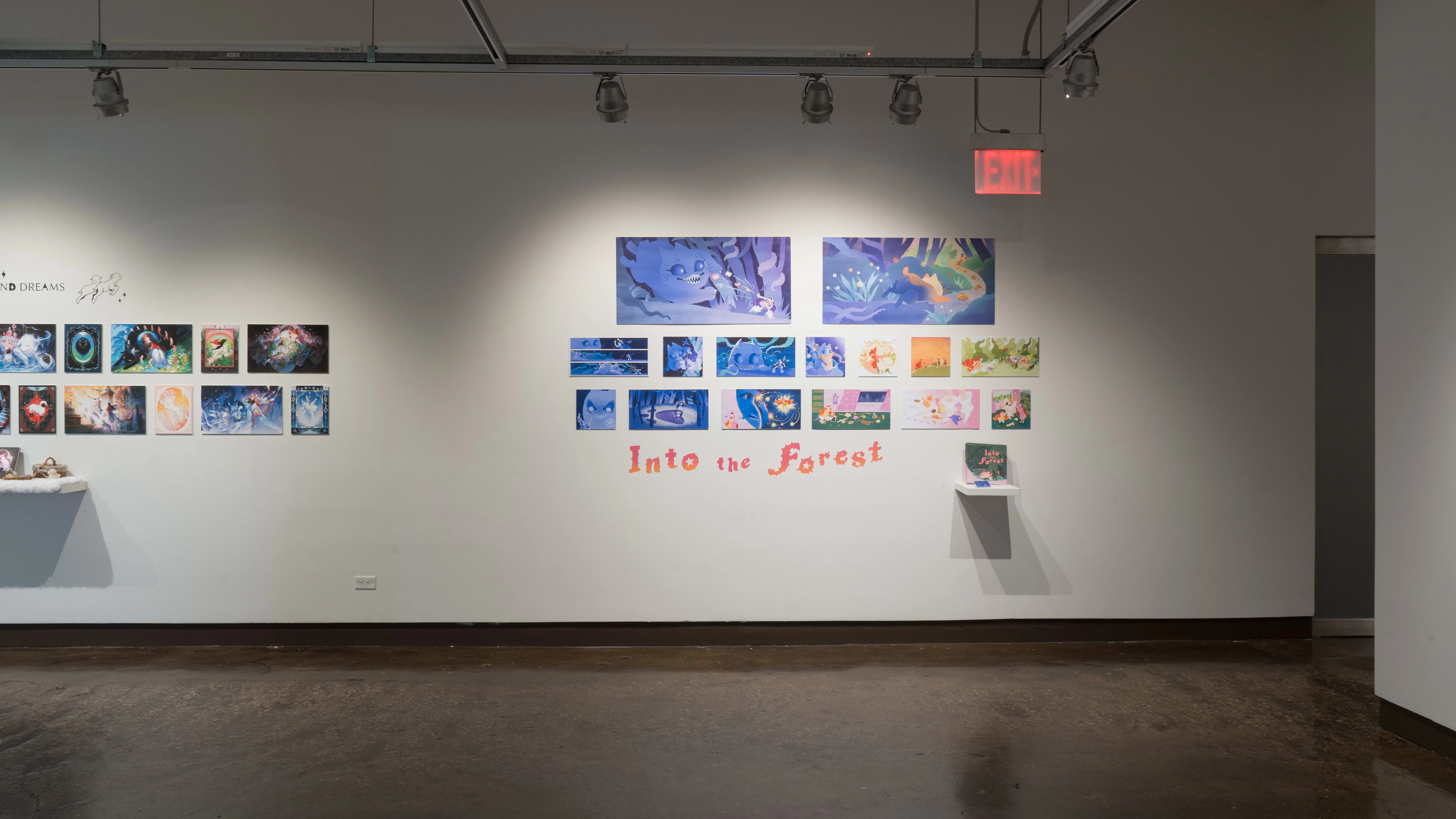 Another view of the north wall, where a project of largely blue, fantastical prints hangs above the title, “Into the Forest.”