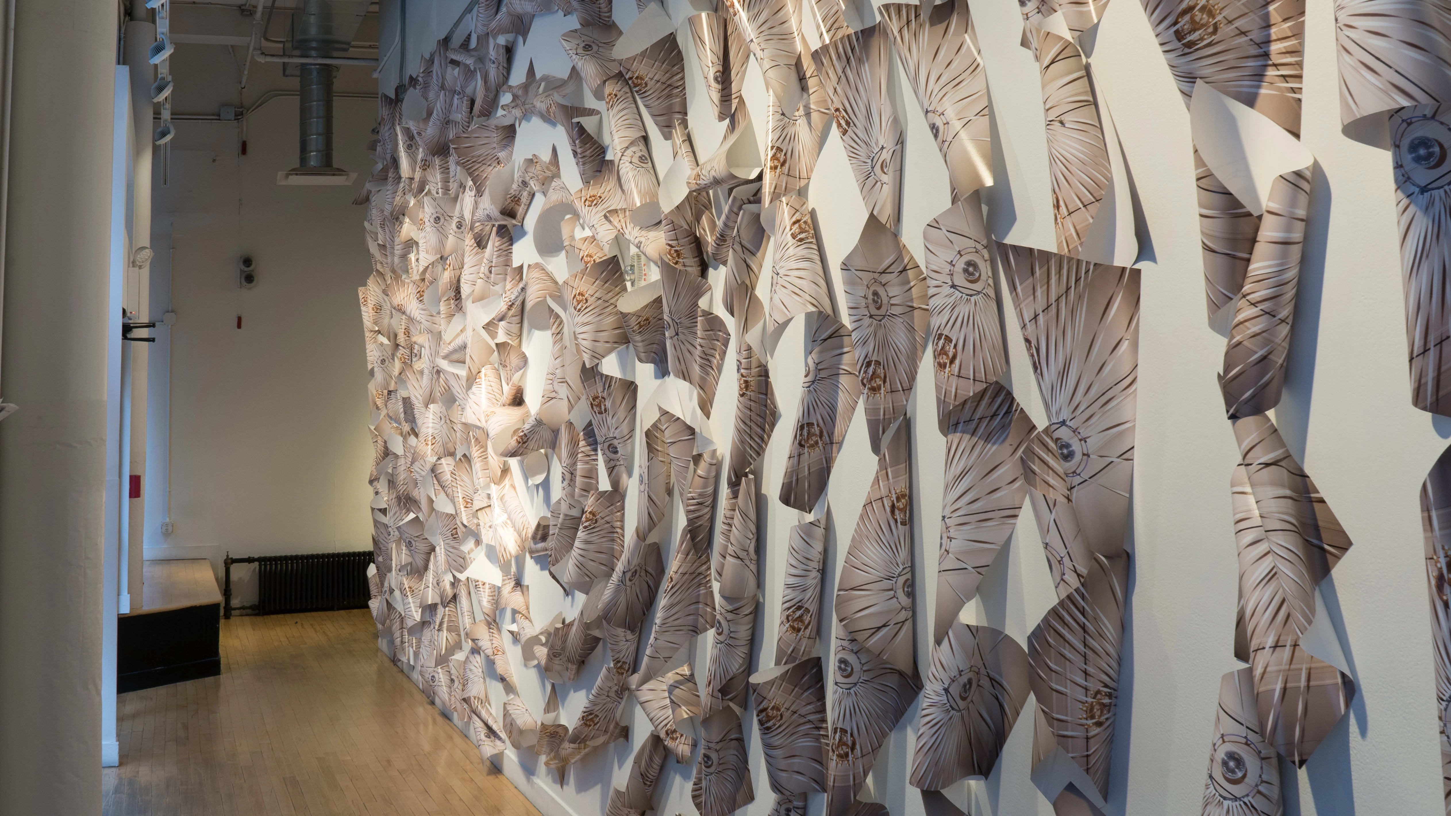 In the SVA Flatiron Windows hallway, many glossy papers are printed with a design that looks like an eye’s cornea. The papers are halfway rolled and pinned on the wall in circles radiating from the center.