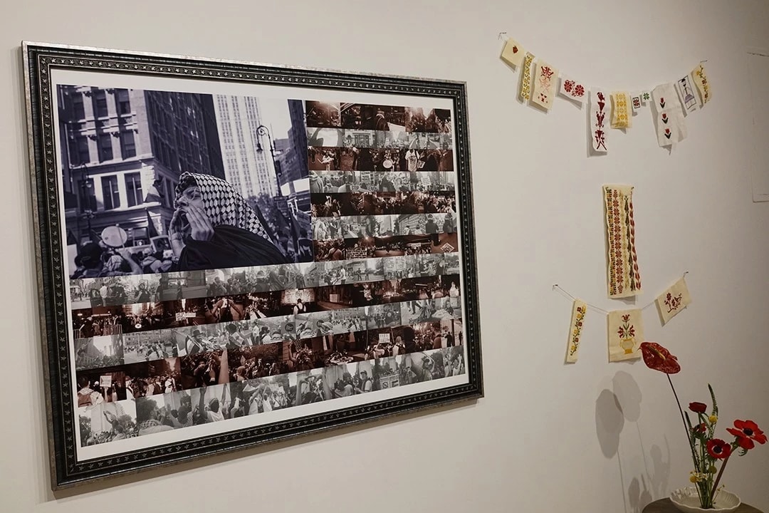 Installation shot of a phtographic collage of protestors, cut and designed to look like the American flag next to red flowers.