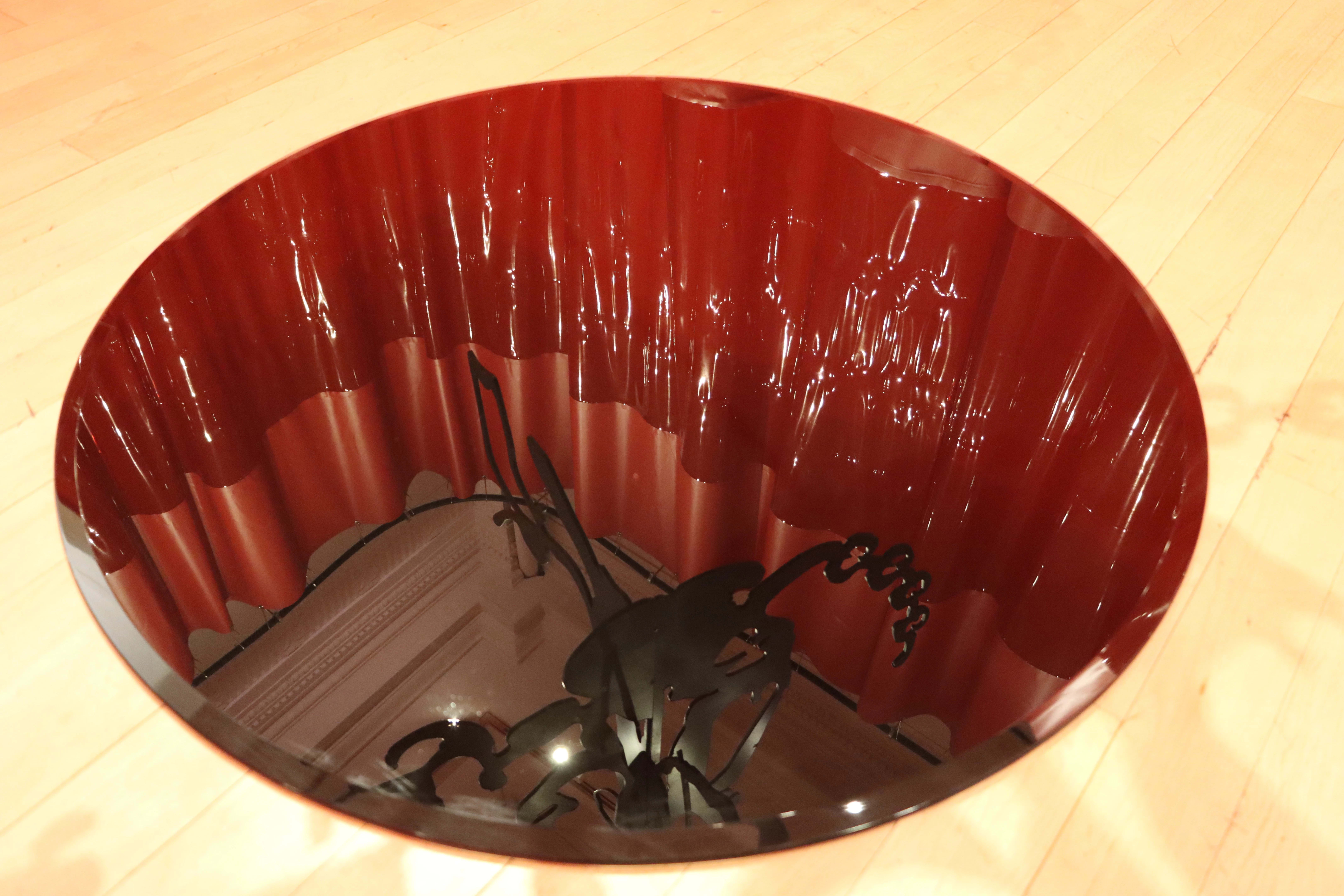 Circle beneath the plexi sculpture, showing a mirror image of the sculpture hanging above it.