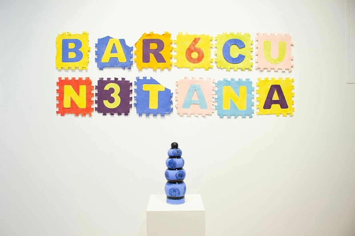 Installation shot of a blue cermaixc structure with a sculpture made of floor tiles behind it.