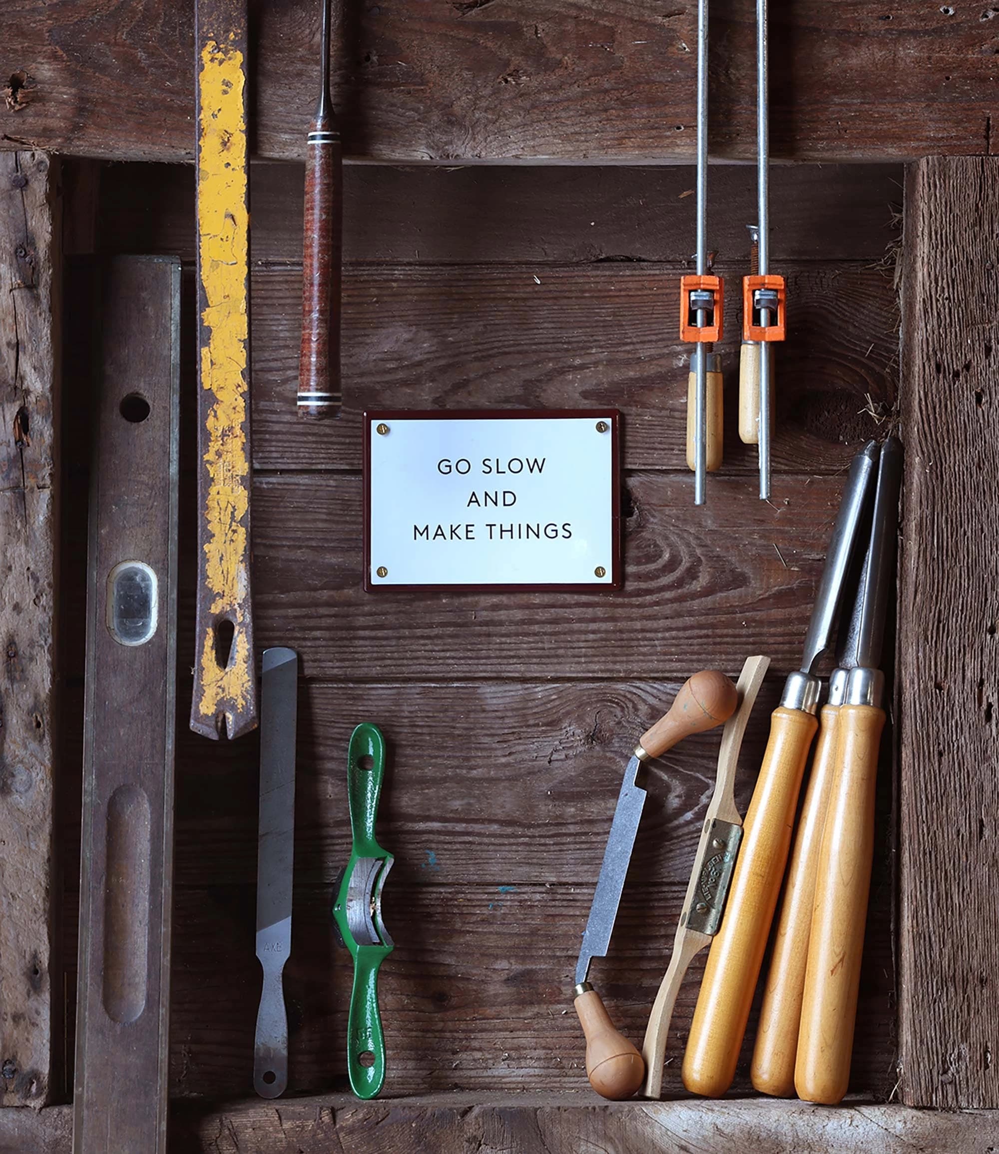 A wooden box featuring a sign that reads "go slow and make things," inviting creativity and craftsmanship.