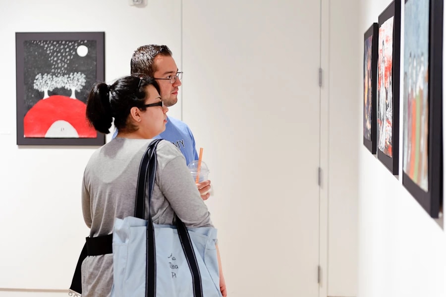 A couple looks at a row of paintings in a gallery space.