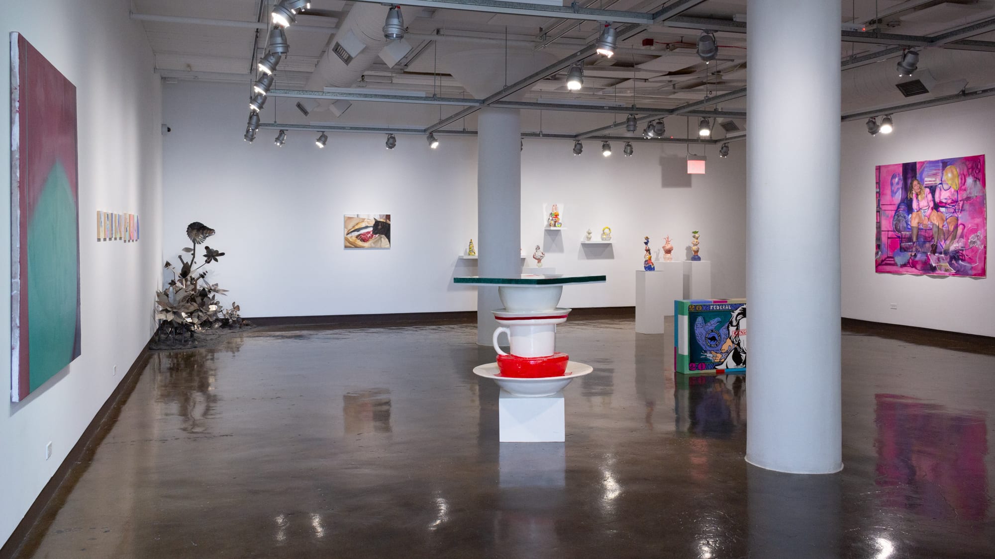 Entry view of first of four spaces at SVA Chelsea Gallery, showing artwork on three walls and several large sculptures sitting on the floor.