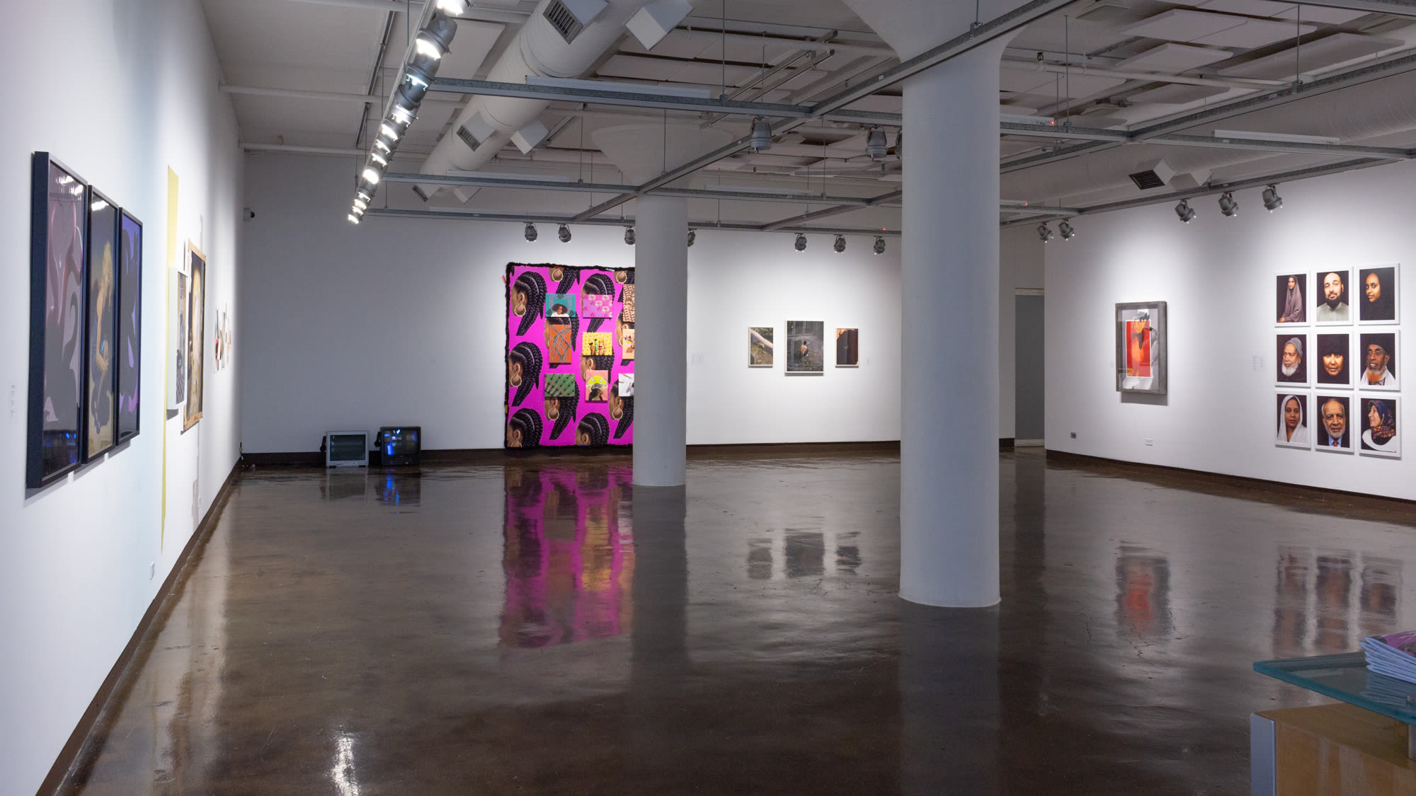 Installation shot of artwork as one enters SVA Chelsea Gallery, showing a variety of photographic and video artworks across three walls.