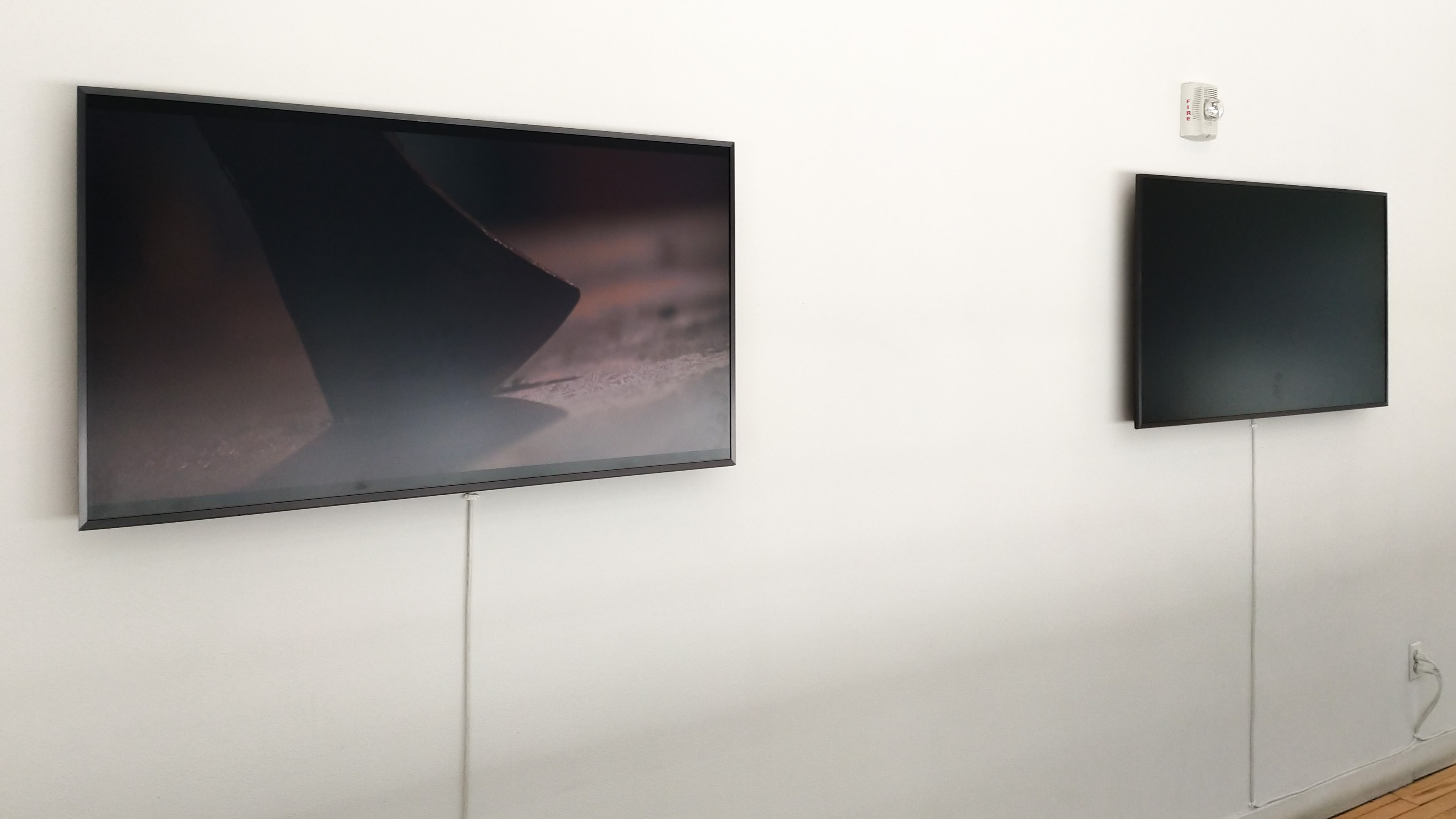 Two monitors on a white wall