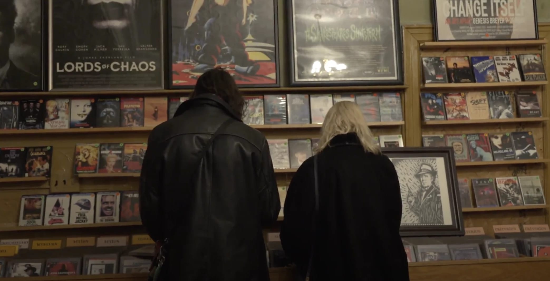 Two people, facing away, looking through DVDs on a shelf 