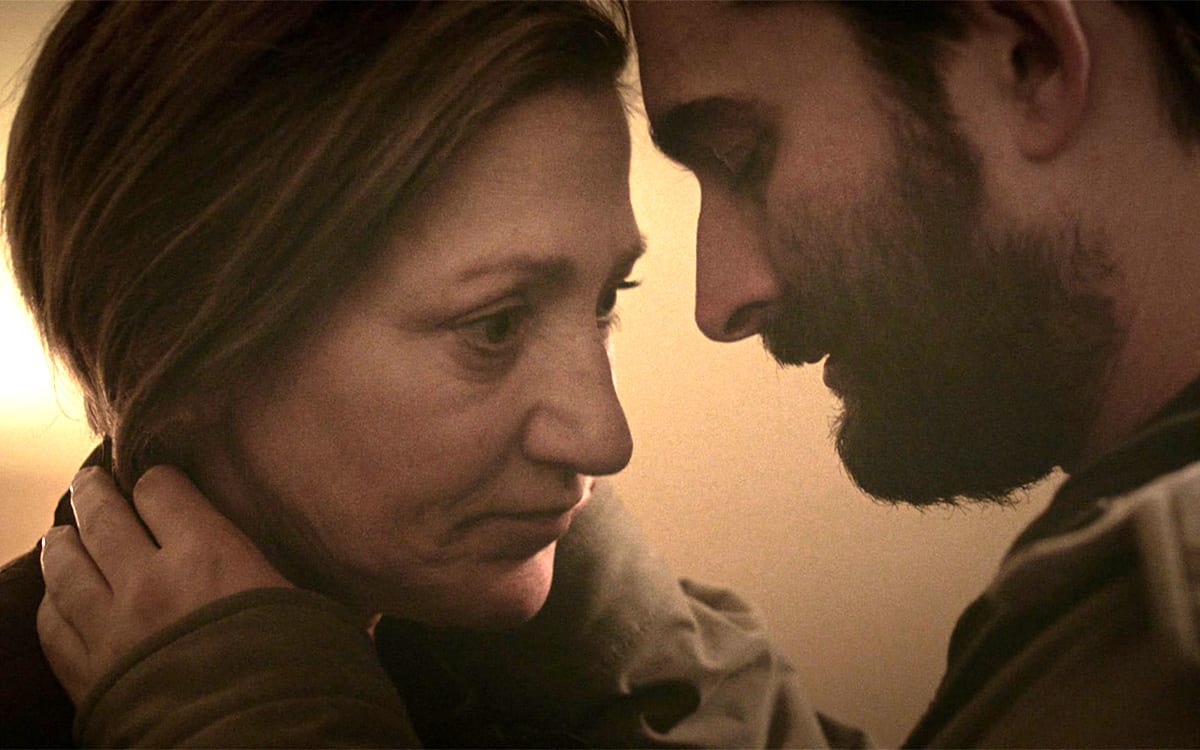 a man embraces a woman while she looks at him