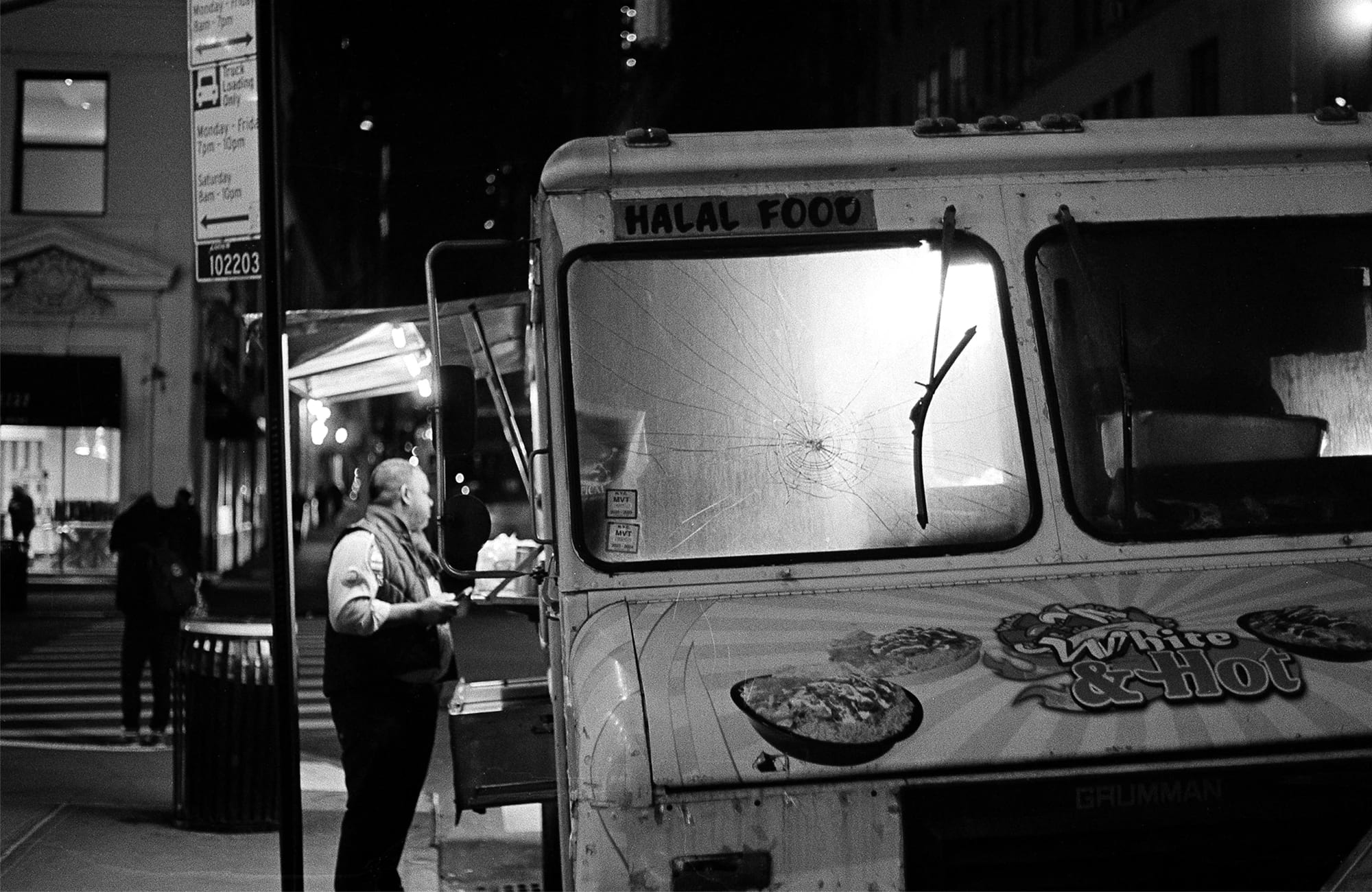 A man stands in front of a food truck at night, buying food.