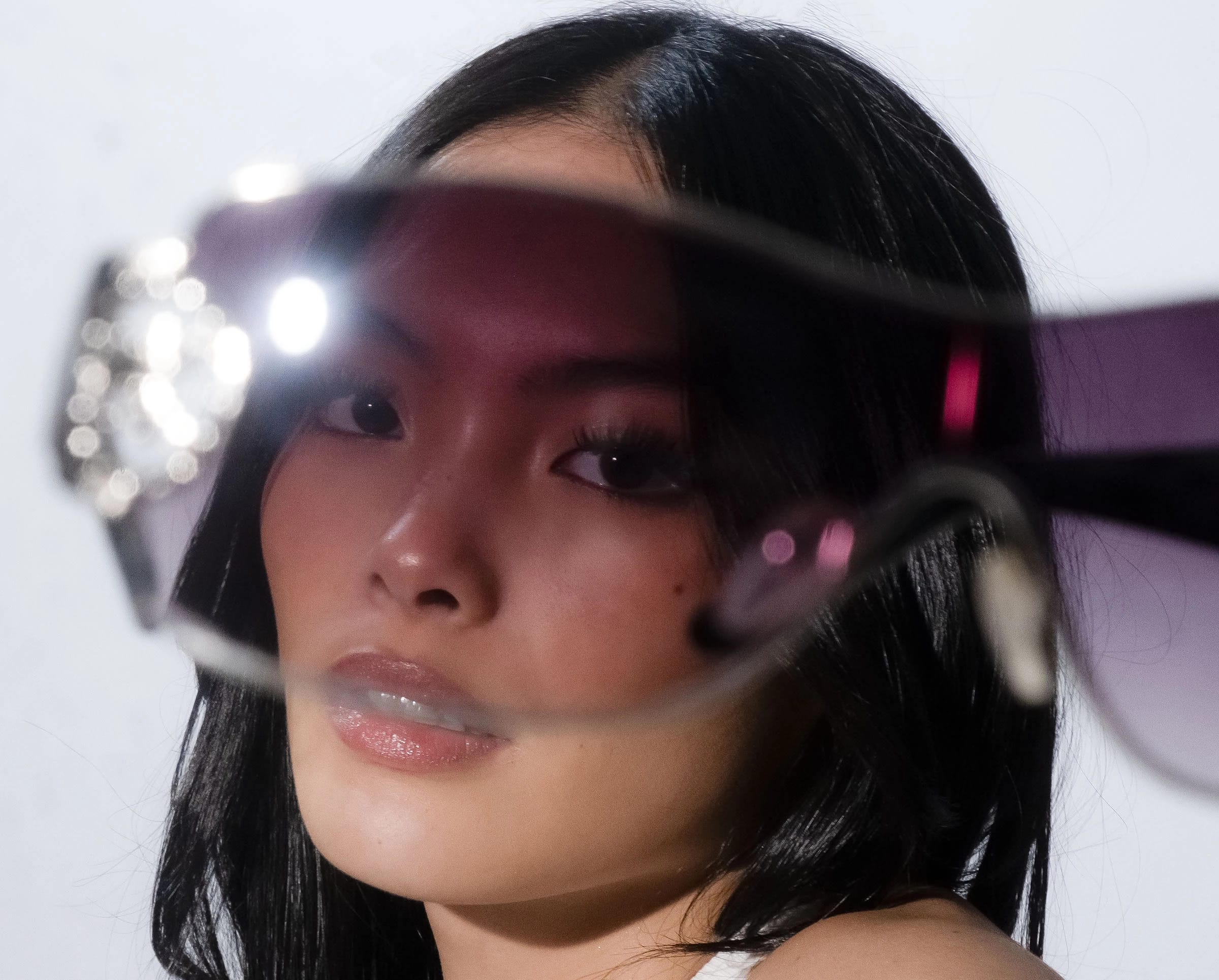 A woman's face peering through glasses 