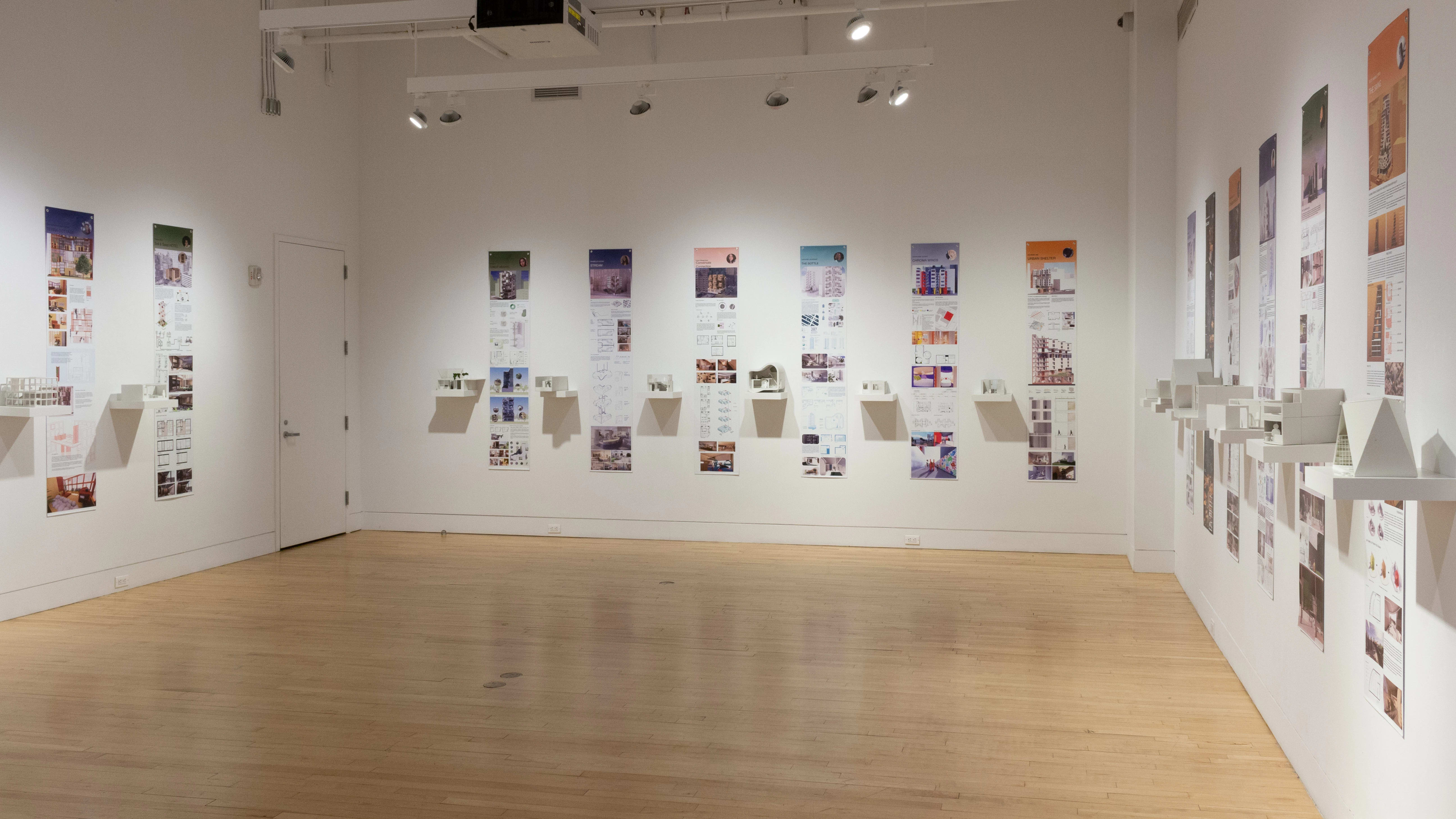 Installation image showing a three walls of a large gallery with building models on shelves, and information banners for each to the right.