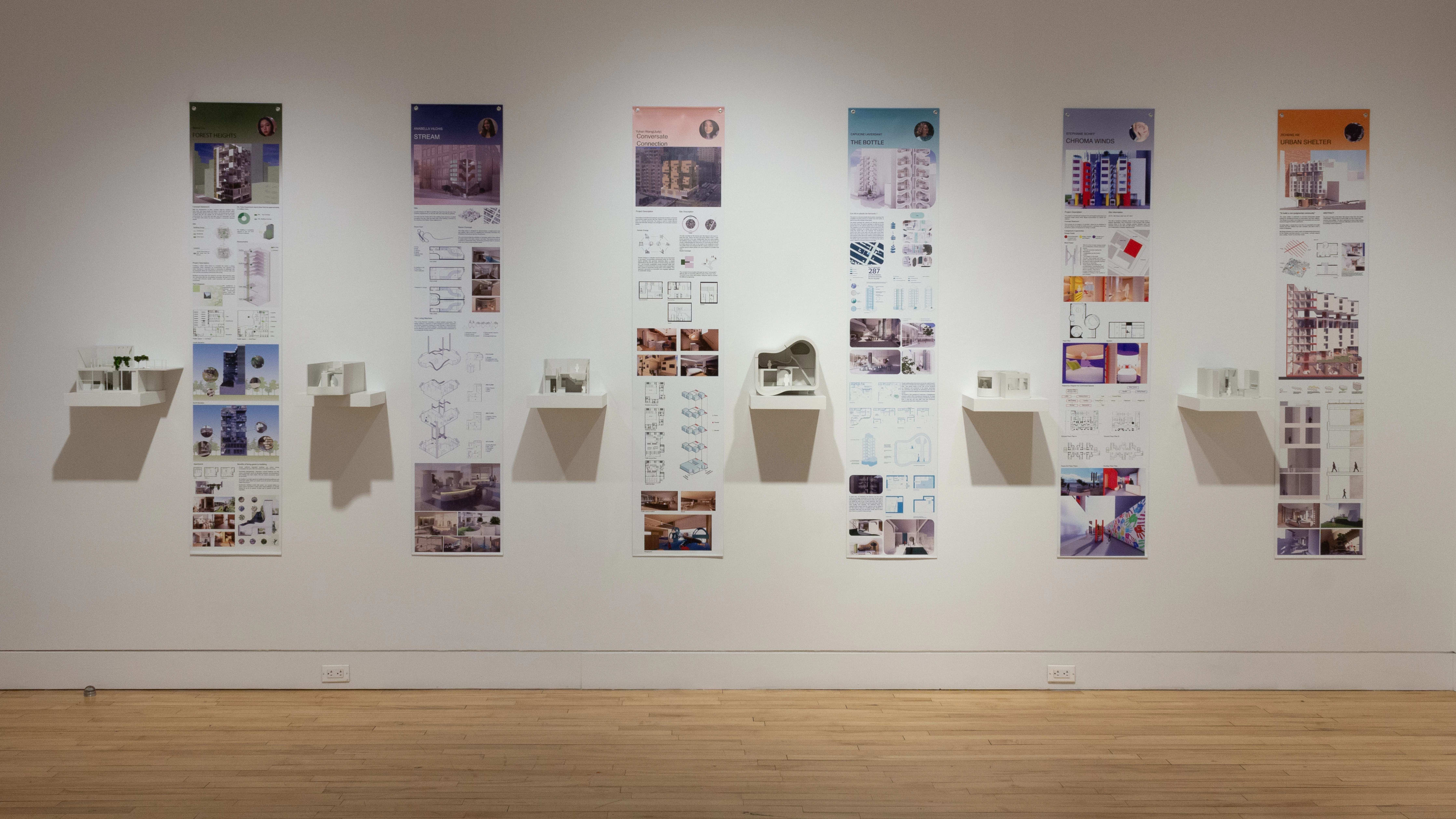Installation image showing a straight view of a gallery wall with six building models on shelves, and information banners for each to the right.