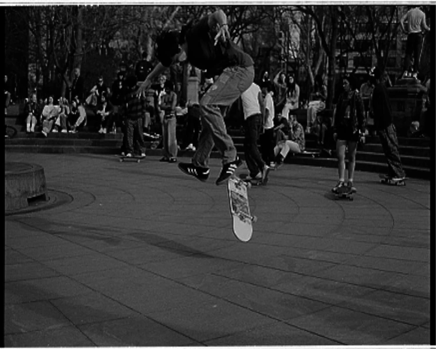 Male skateboarder doing a kickflip photographed mid-air.