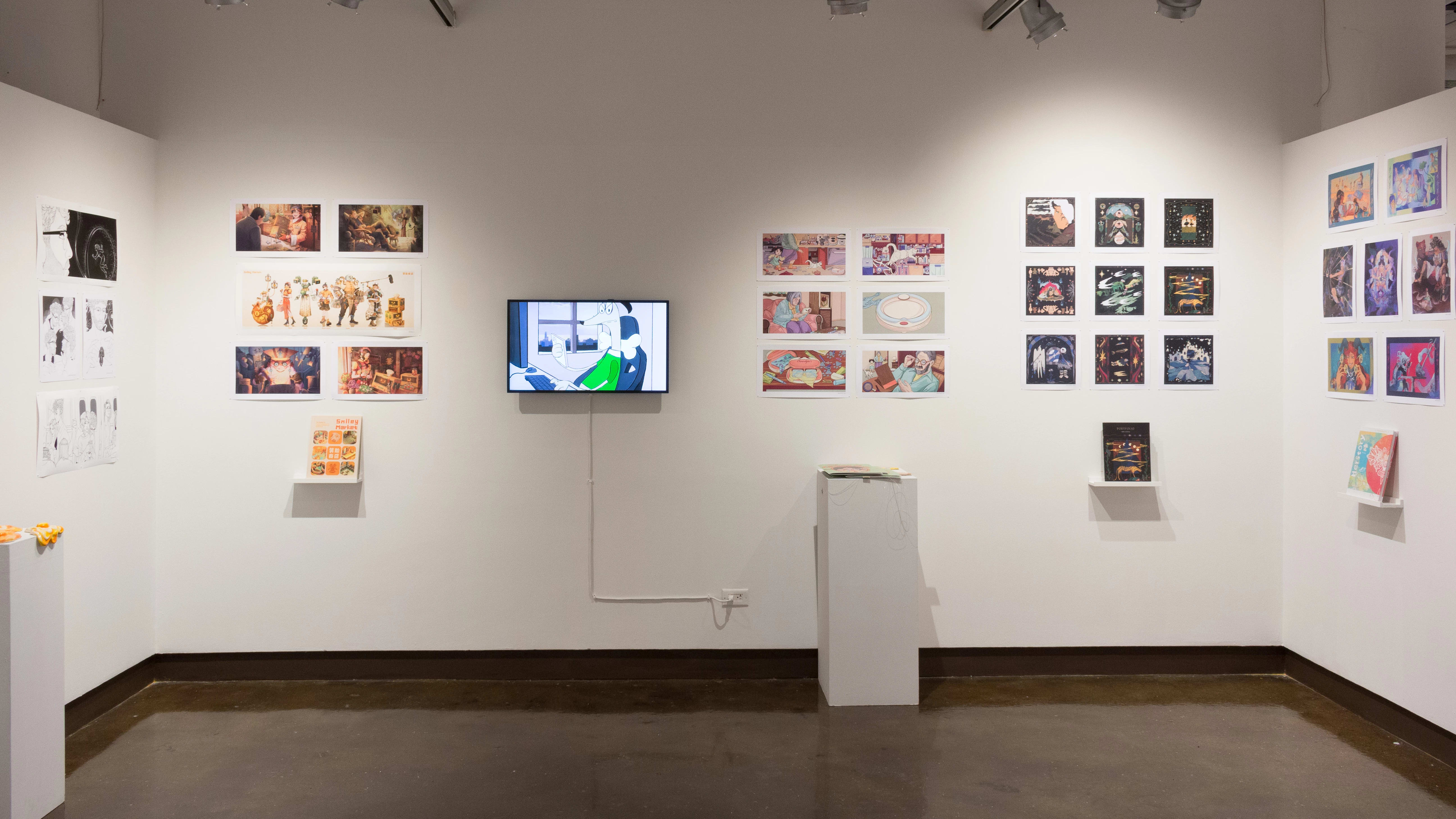 In the alcove of the third gallery space, more student work is displayed in the form of prints and books. However, there is also a monitor playing animations, and a pedestal holding some ceramic sculptures of fried eggs.