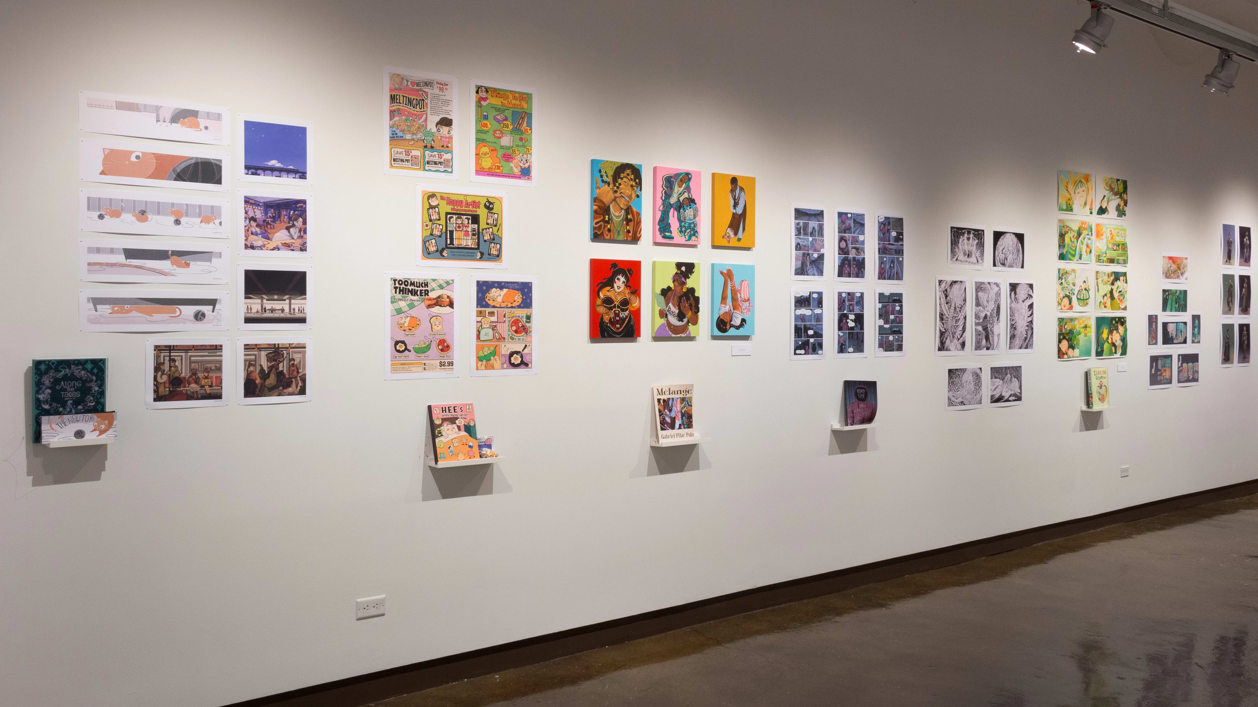 Prints, originals, and books are all displayed on a wall of gallery three.