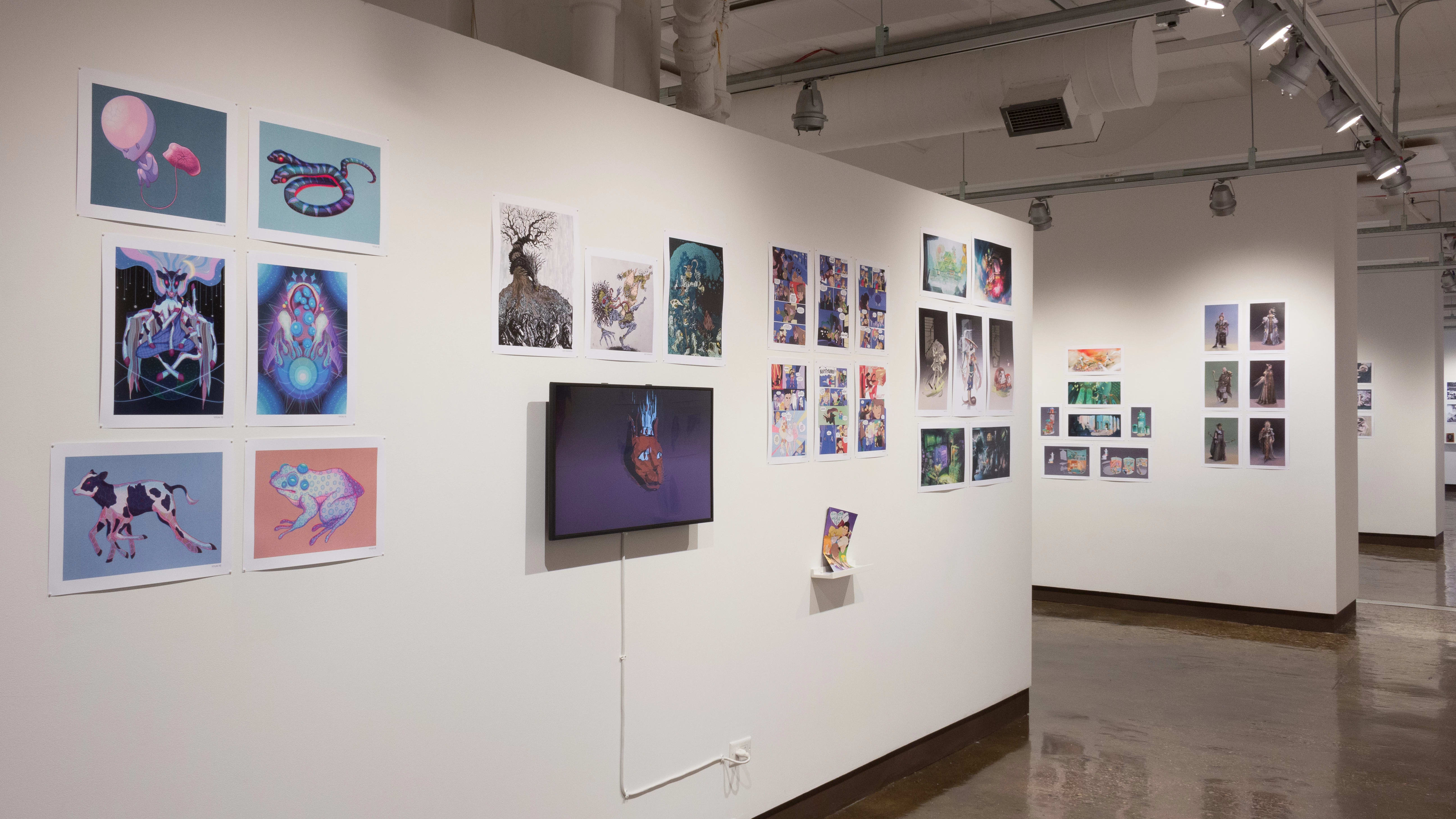The prints hanging on the walls vary in dimension, style, and color. A monitor displaying an animation hangs in the middle of the wall, surrounded by the prints.