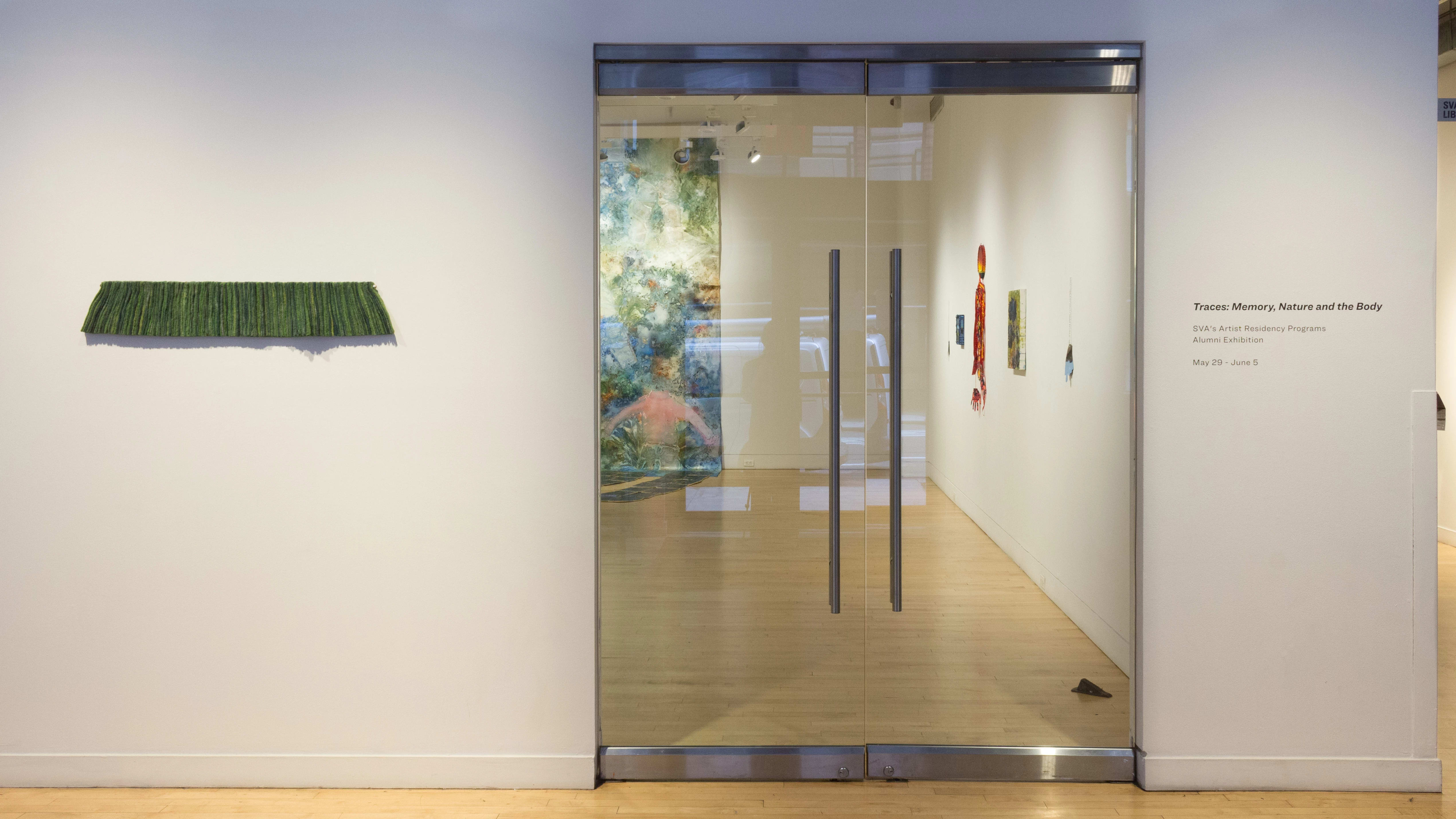 A view of the entrance of the SVA Flatiron Gallery highlights a single sculpture piece and vinyl signage that reads “Traces: Memory, Nature and the Body, SVA’s Artist Residency Programs Alumni Exhibition”