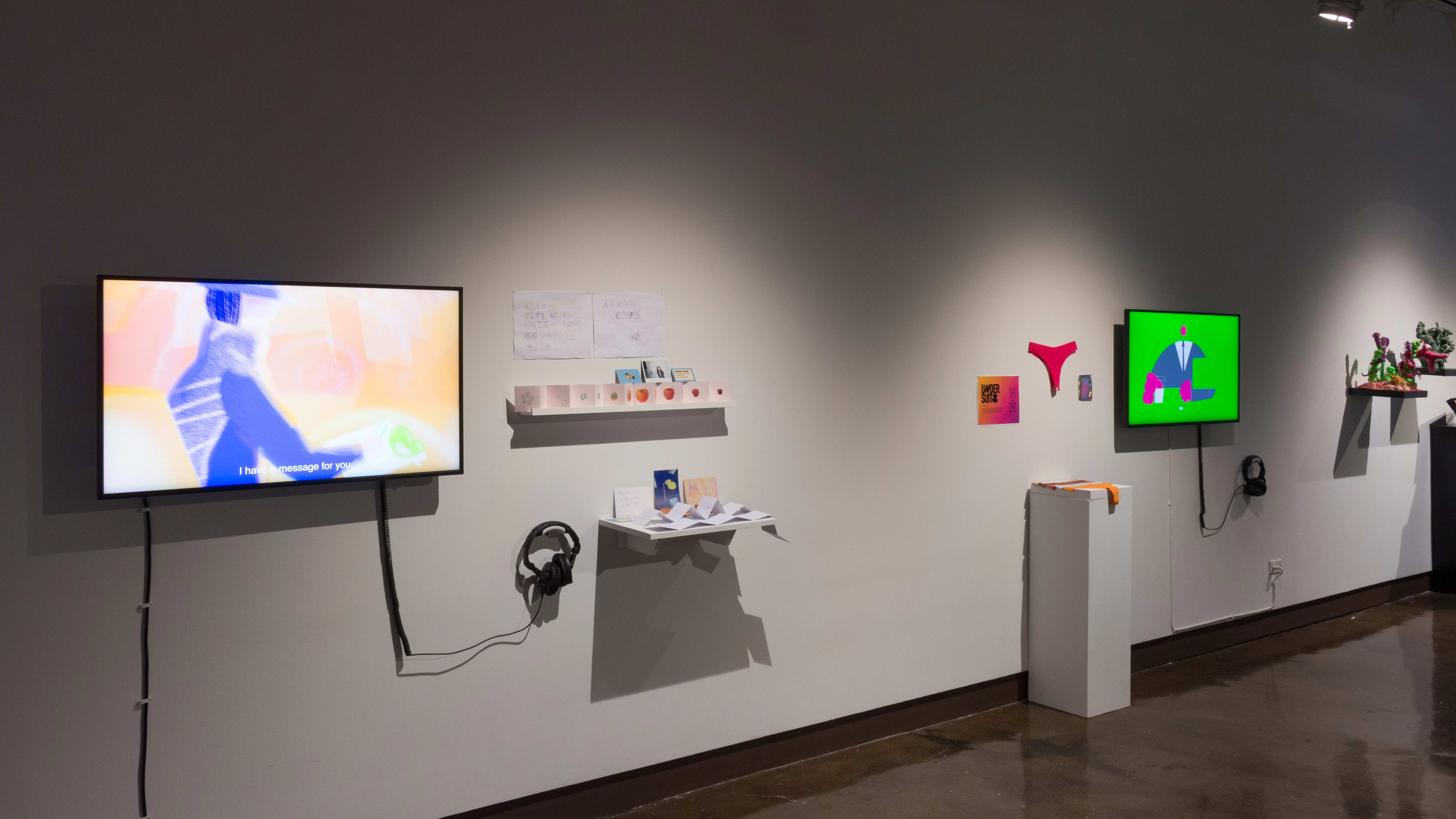 Angled wall with two monitors and several shelves and pedestals visible, receding into the background.