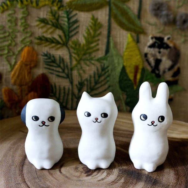 A photograph of three small ceramic sculptures of a dog, a cat and a rabbit.