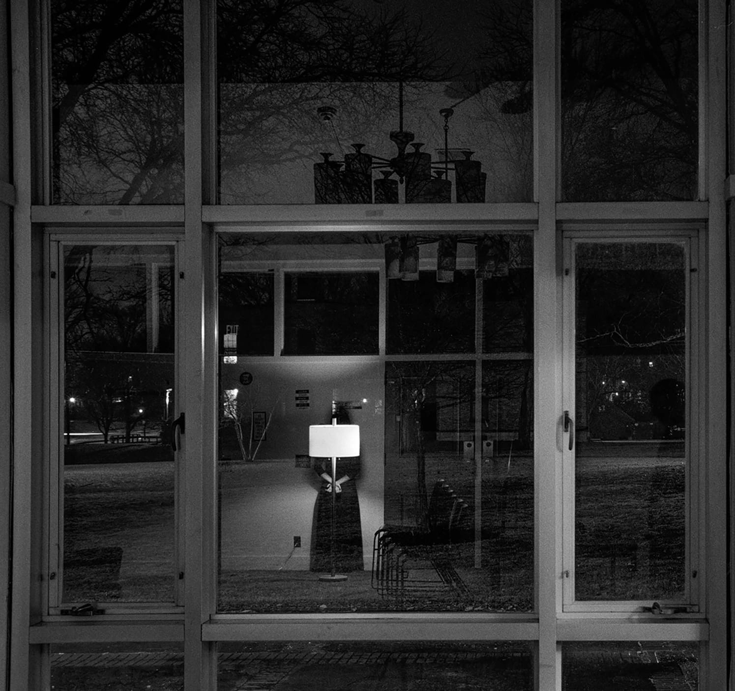 A black and white photo displays reflections in a window and the scenery outside.