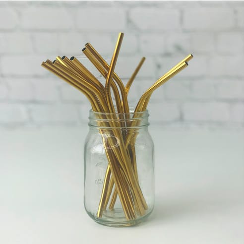 A color photograph of gold-colored stainless steel drinking straws in a jar.