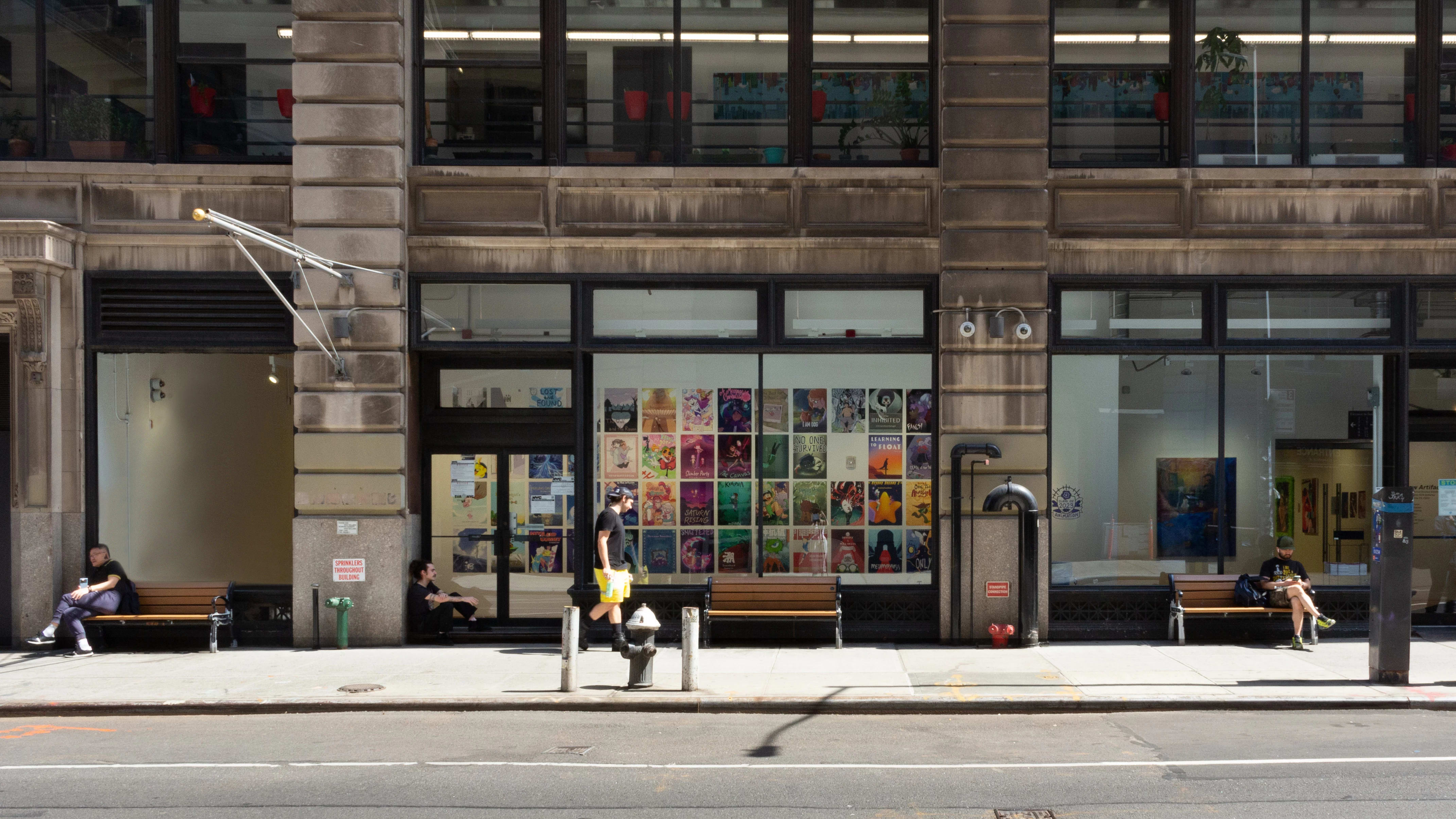 Street view of large windows with posters lining a hallway inside.