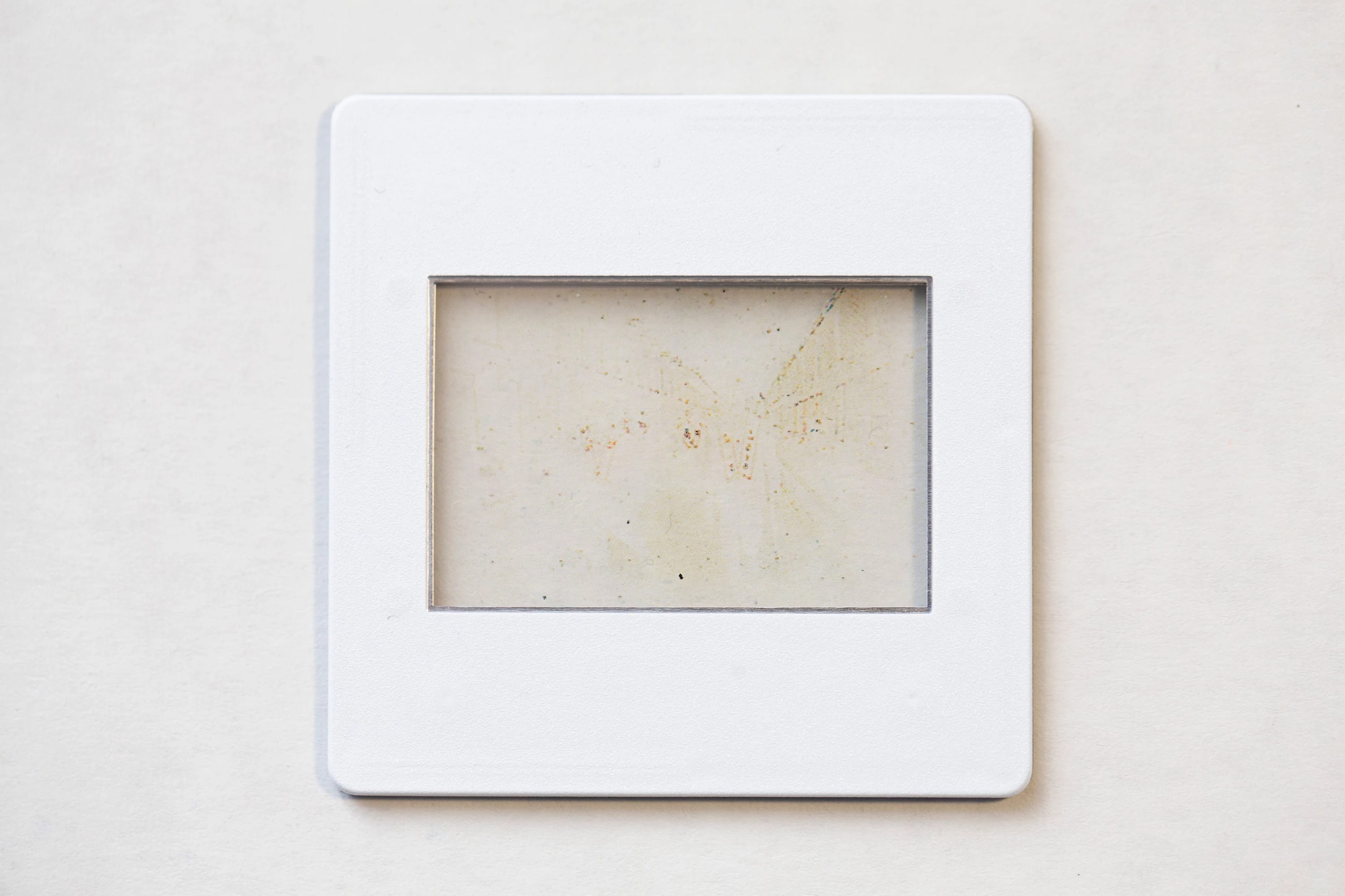 A Slide in plastic holder with content removed leaving dust, grain and fungus.