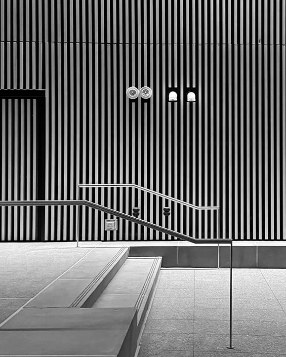 Interior Black and White of a Corporate Building Entrance, with captivating stripes for verticality texture and streamlined steps in front. 