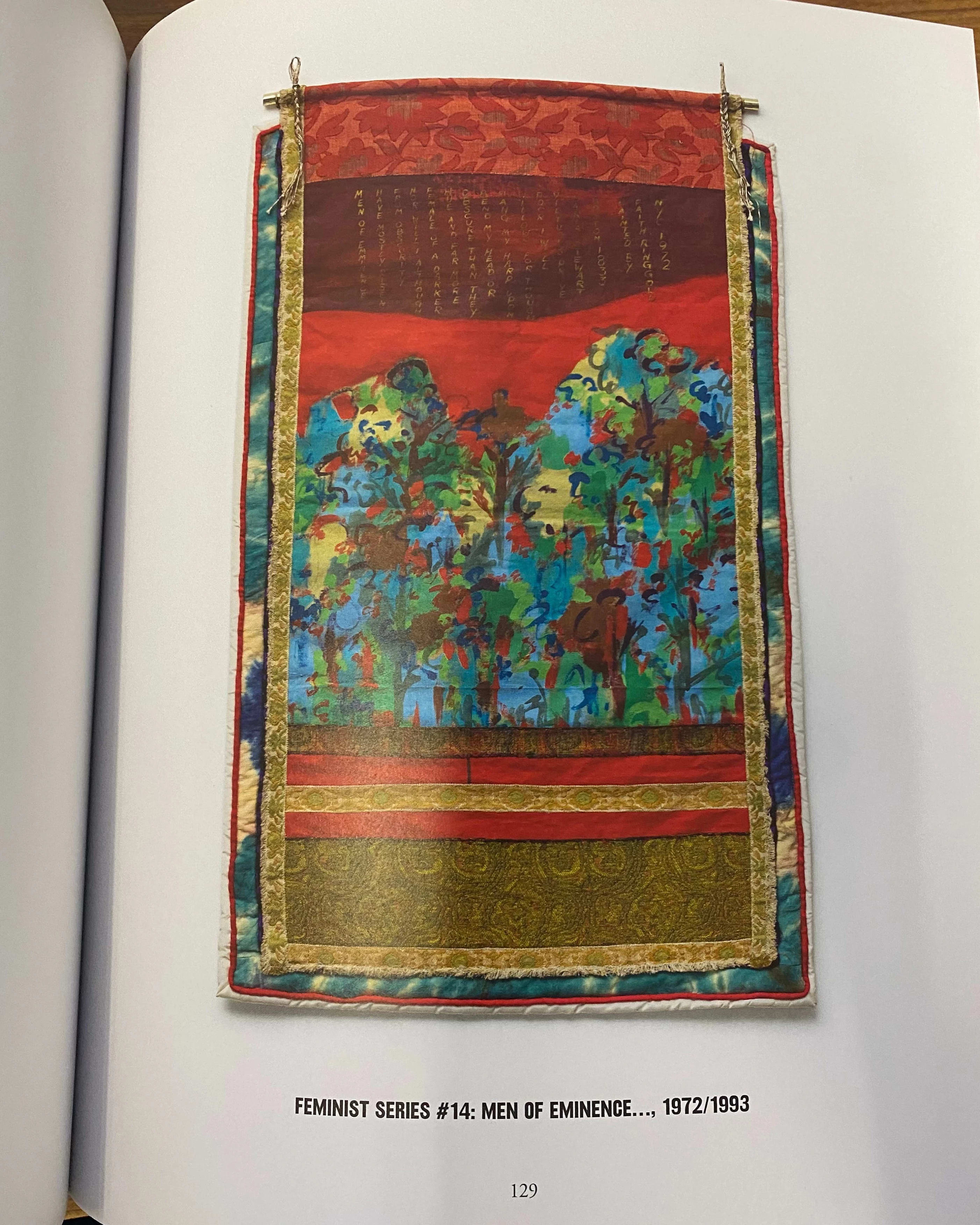 Picture of a book with a picture of one of Faith Ringgold's quilts, with different gold and blue patterns framing the central image of an abstract forrest with a red background and some small gold text at the top. 