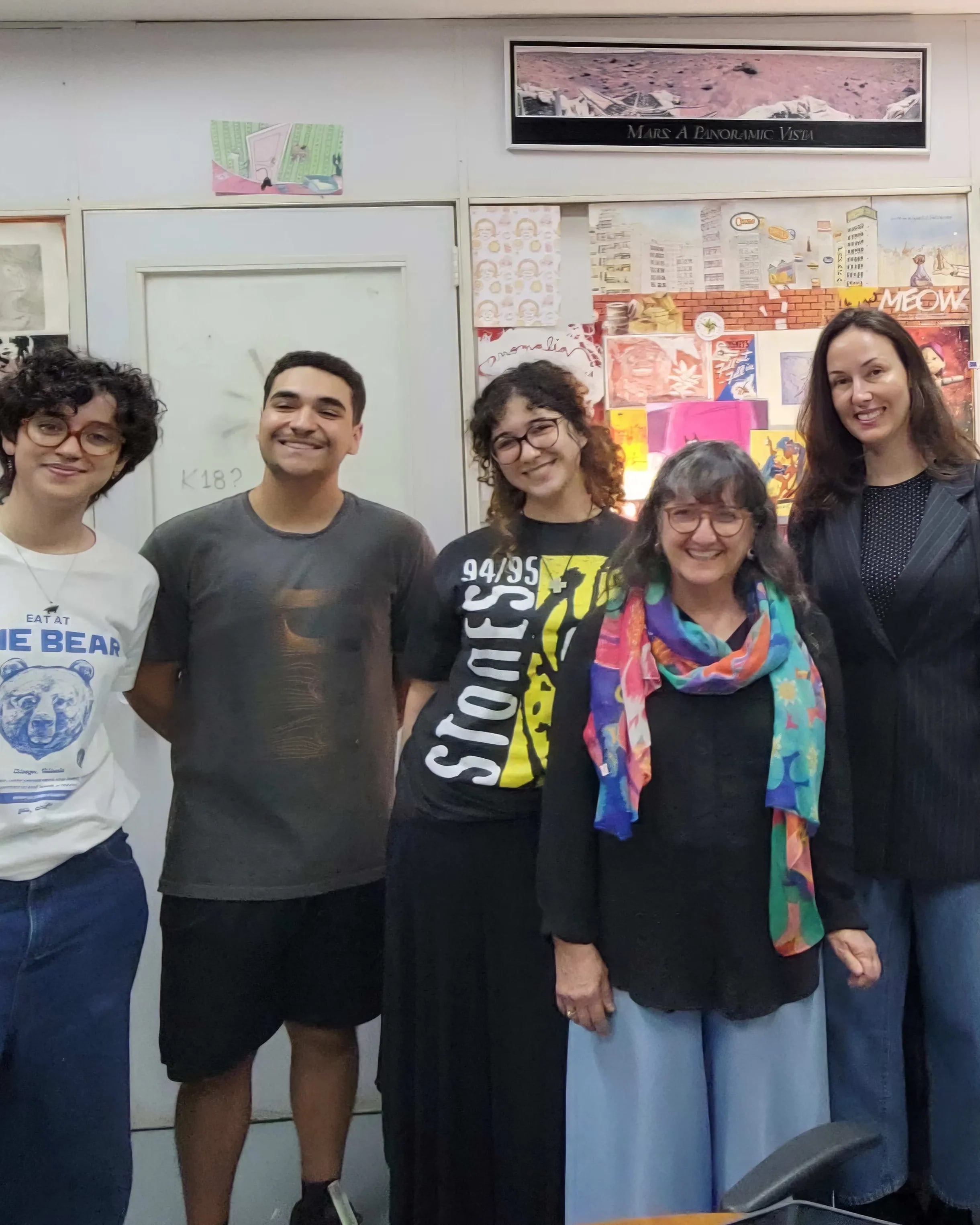 A group of five people pose for a photo in a studio space