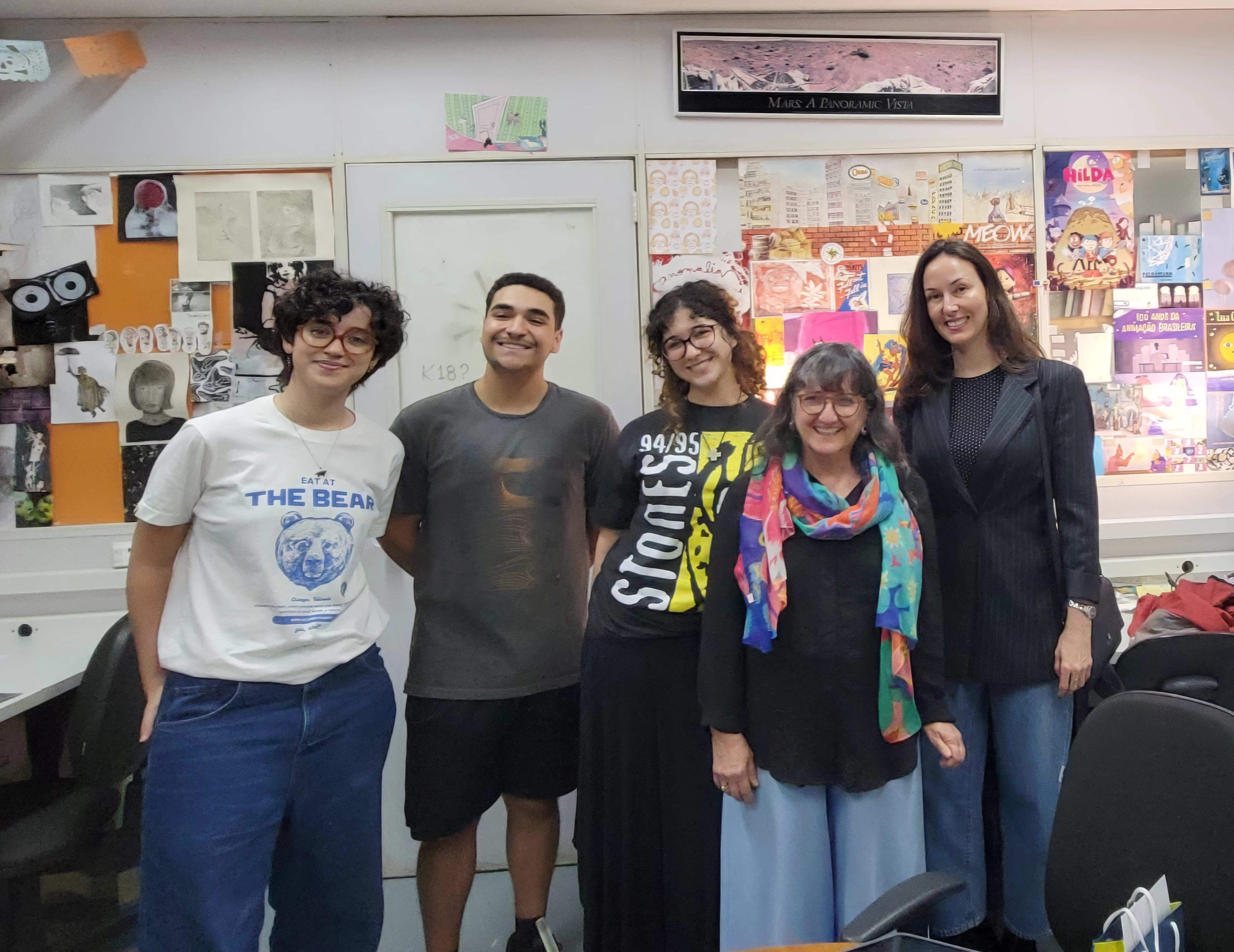 A group of five people pose for a photo in a studio space