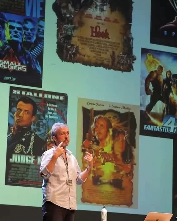 Man presenting in front of a projection with various movie posters