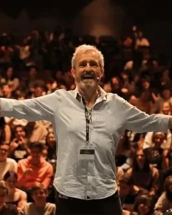 Man stands with arms open, smiling in front of a crowd of people