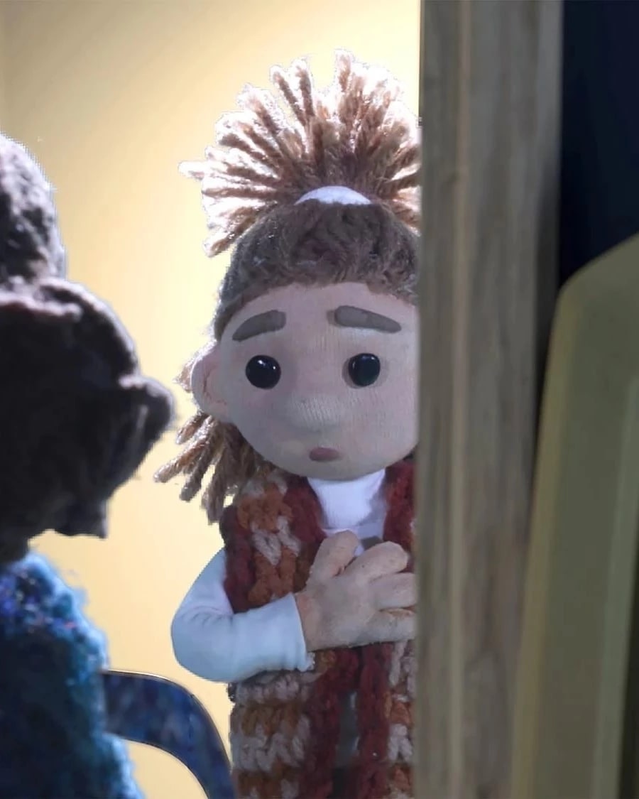 Backlit, a little girl peers into a dark room speaking to another girl.