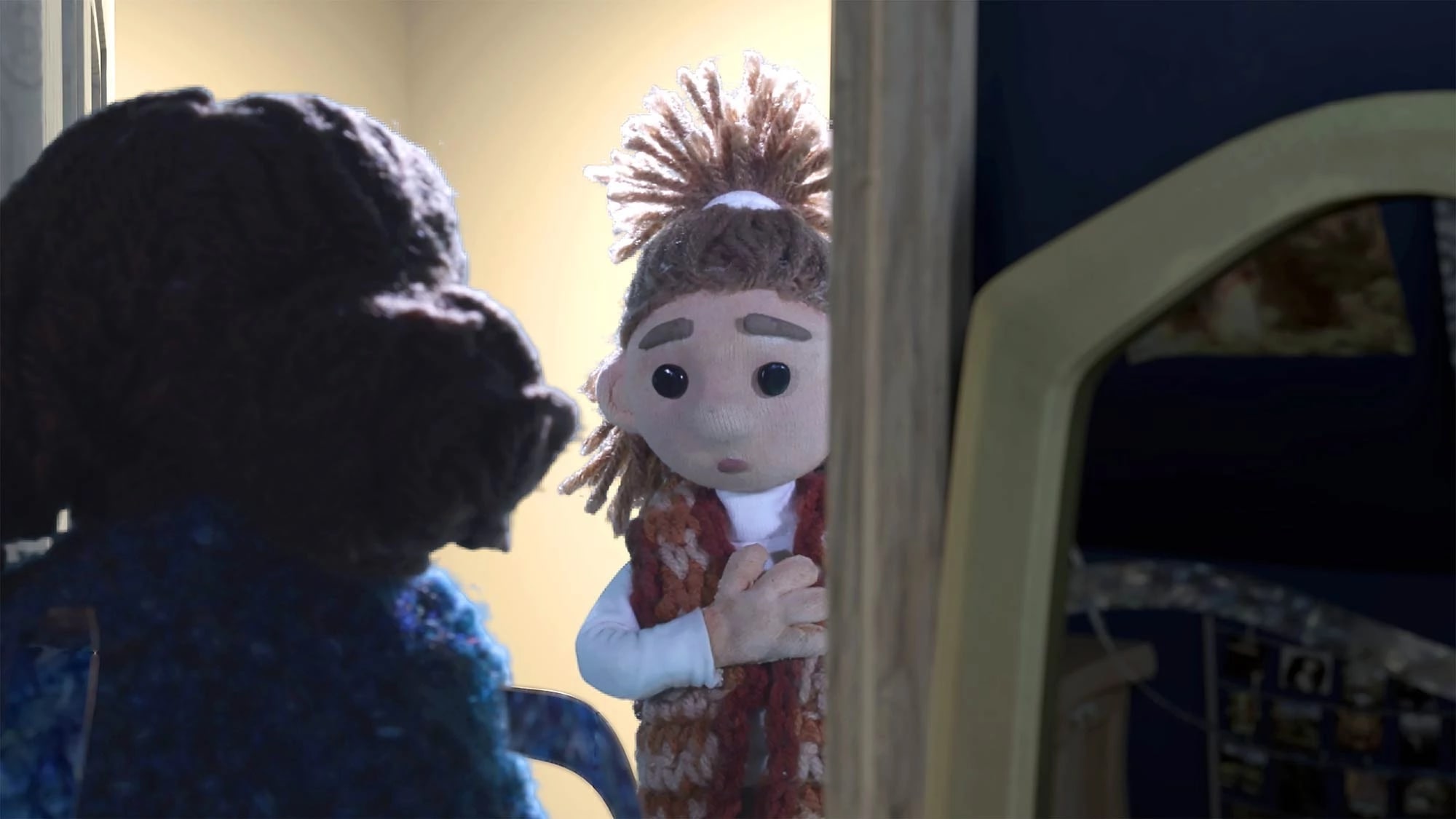 Backlit, a little girl peers into a dark room speaking to another girl.