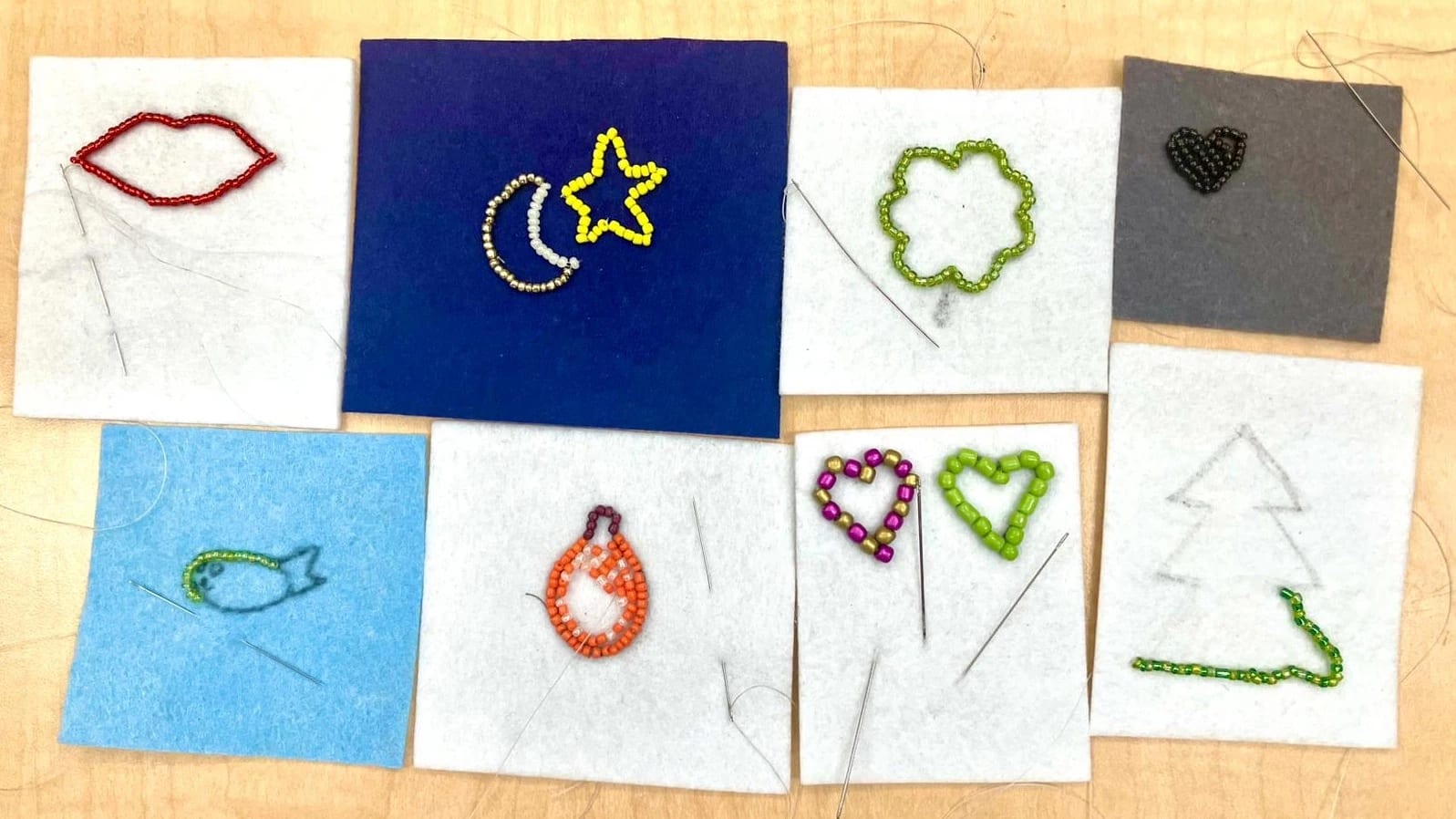 Rectangle shaped felt pieces with embroidery designs of moons, stars, hearts, trees, and fish