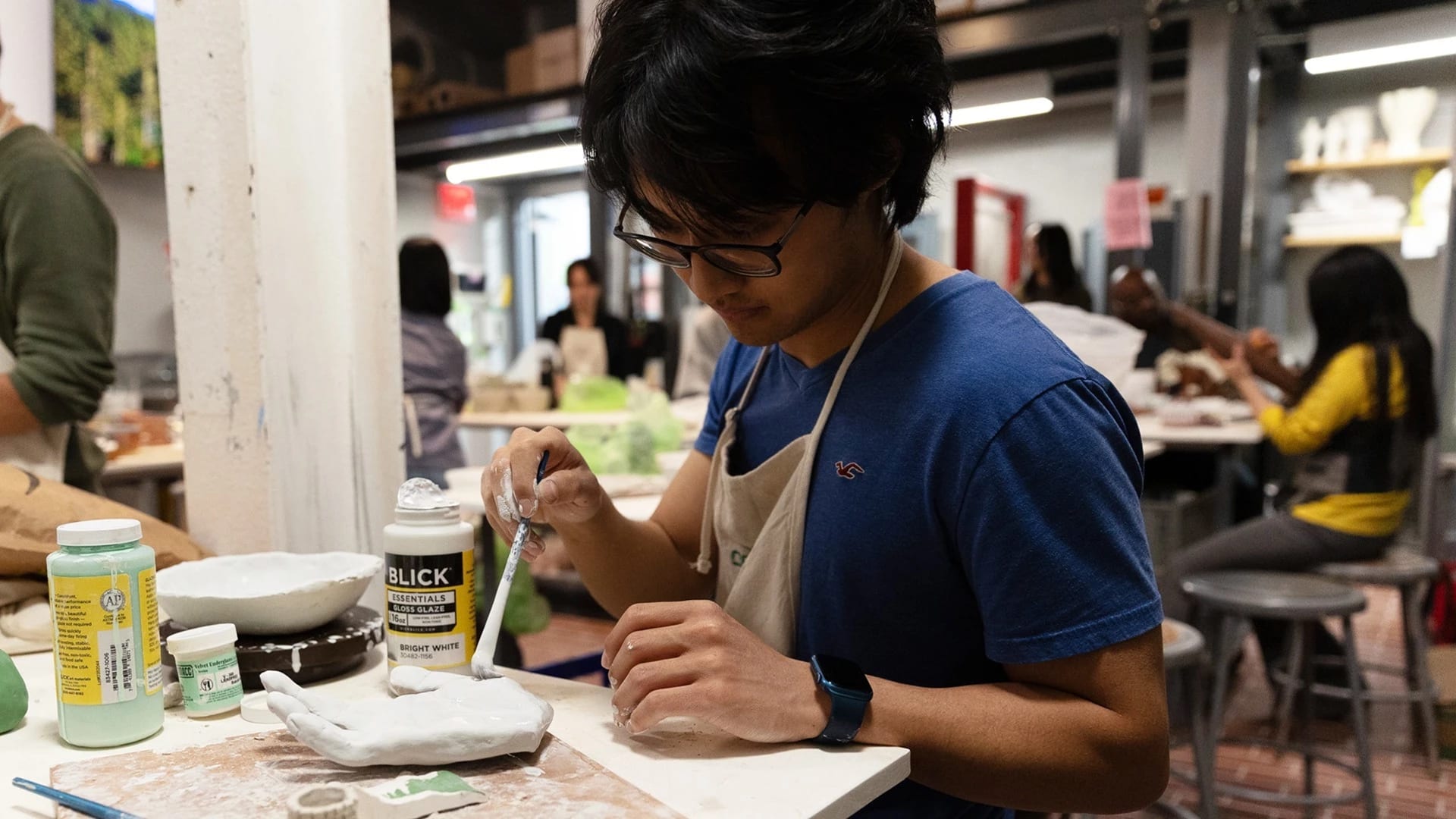 student glazing a ceramic hand