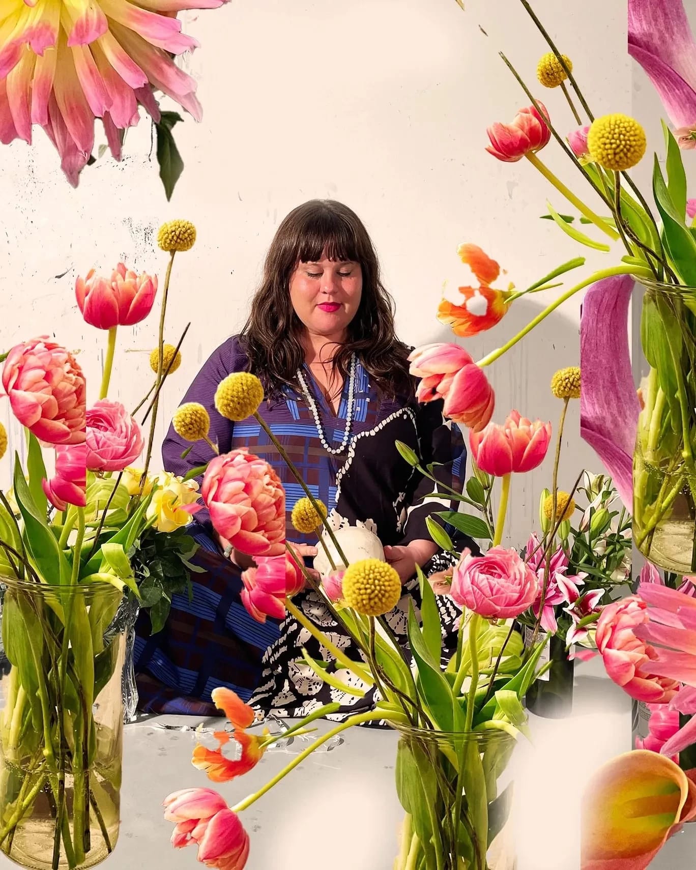 A woman with long hair sits meditating among the flowers.
